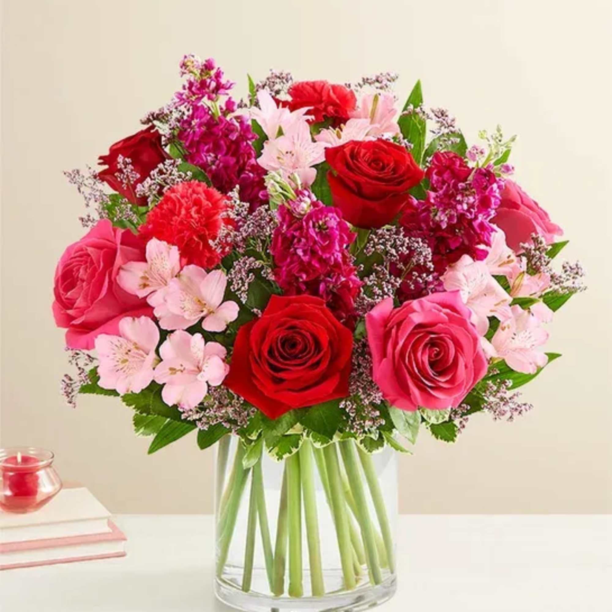 Bouquet of red and pink roses with pale pink flowers in a clear glass vase
