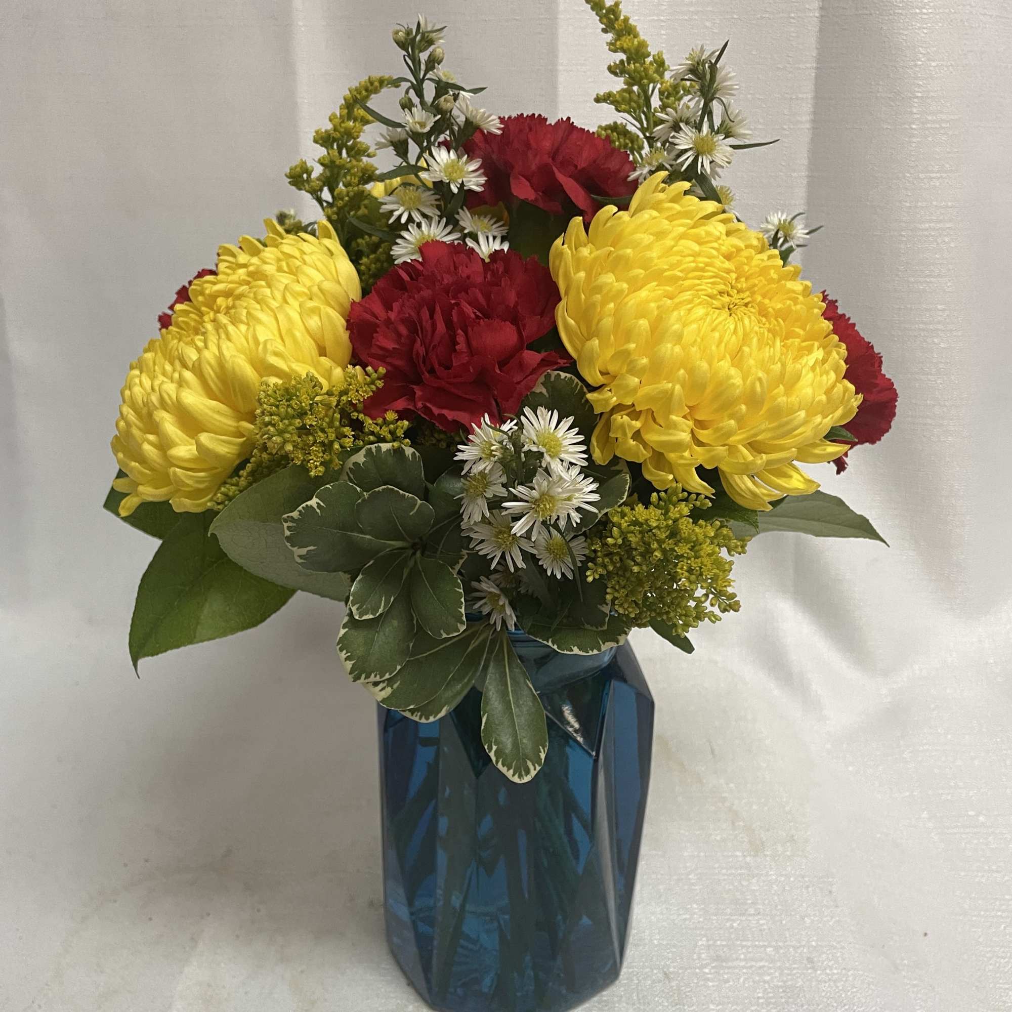 Yellow and red flowers arranged in a blue vase