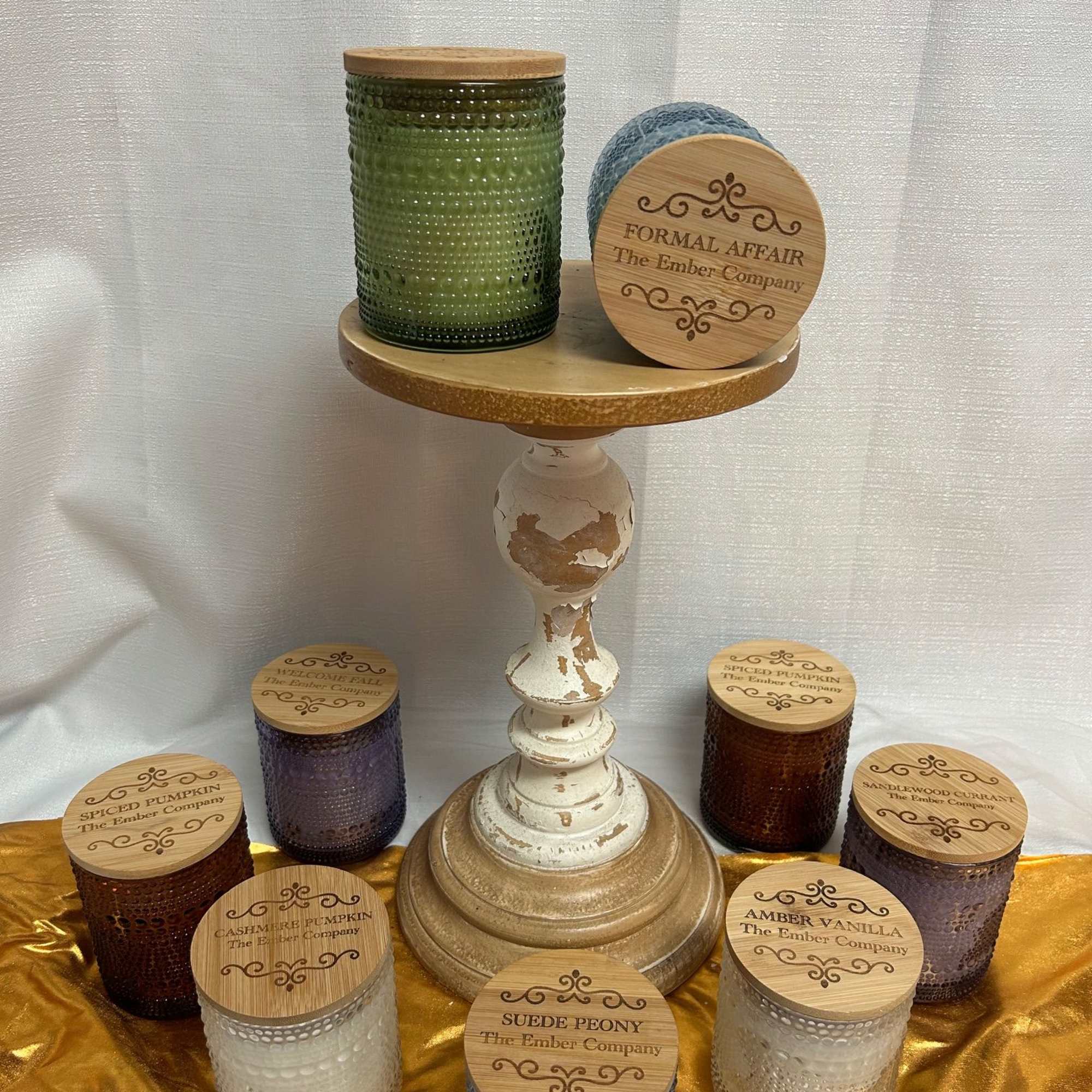 Assorted scented candles in textured glass jars on a pedestal stand