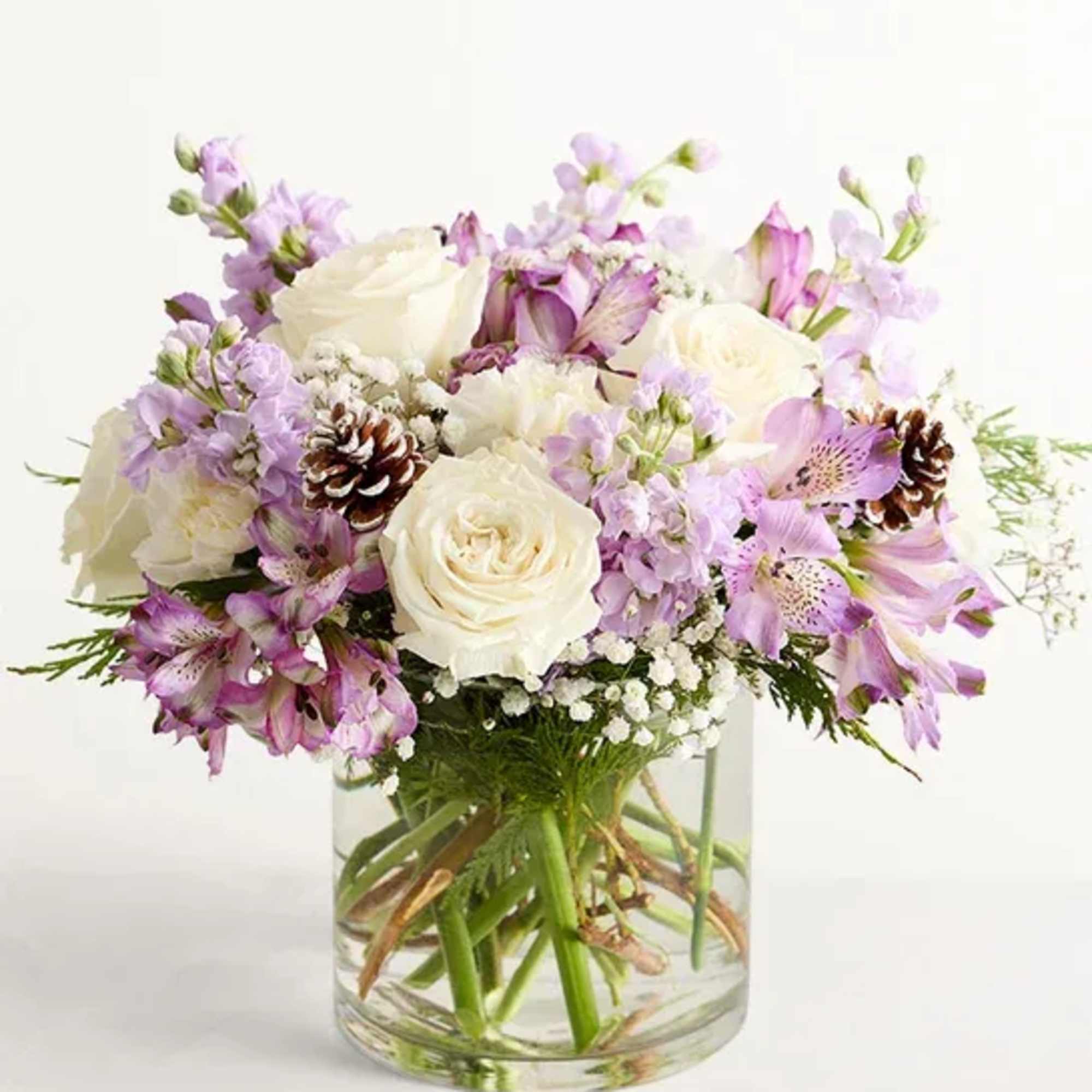 Bouquet of white roses and lavender flowers in a clear glass vase