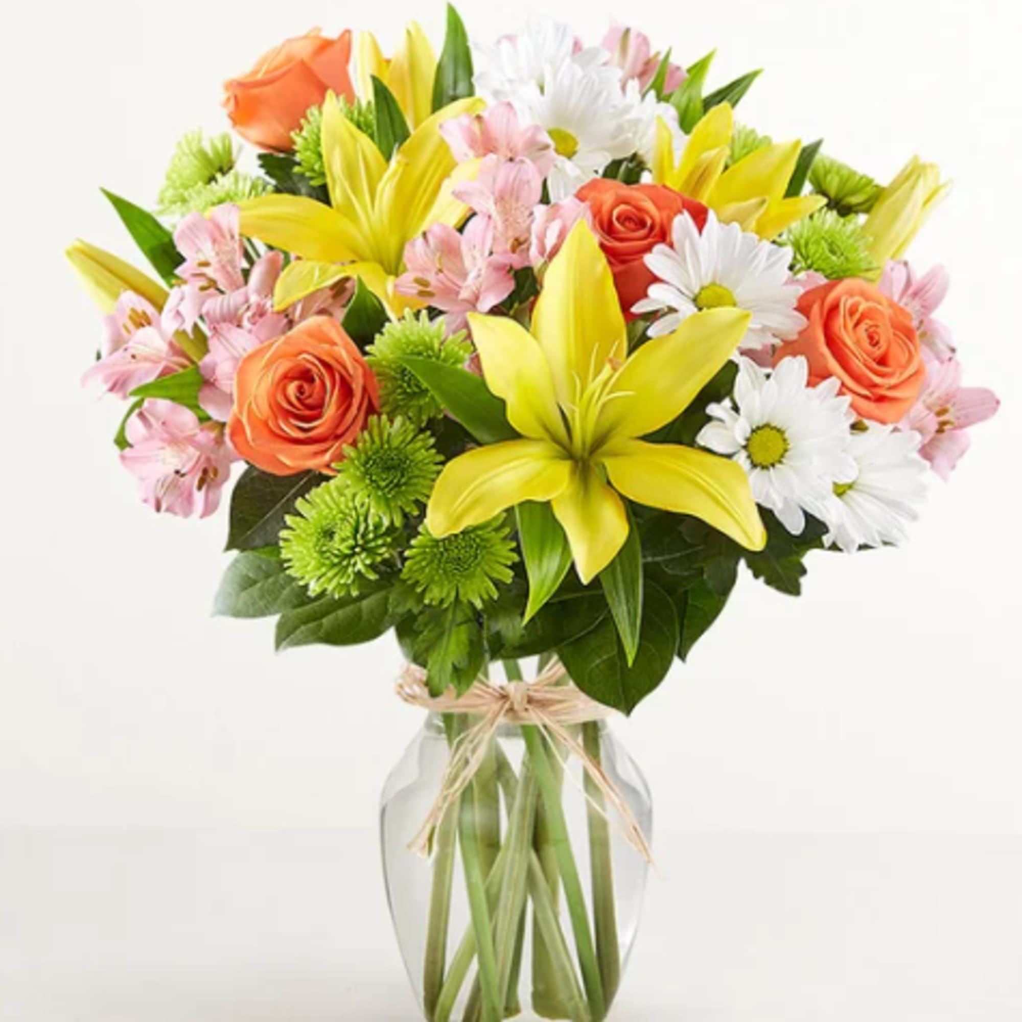 Bouquet of yellow lilies, orange roses, and white daisies in a glass vase