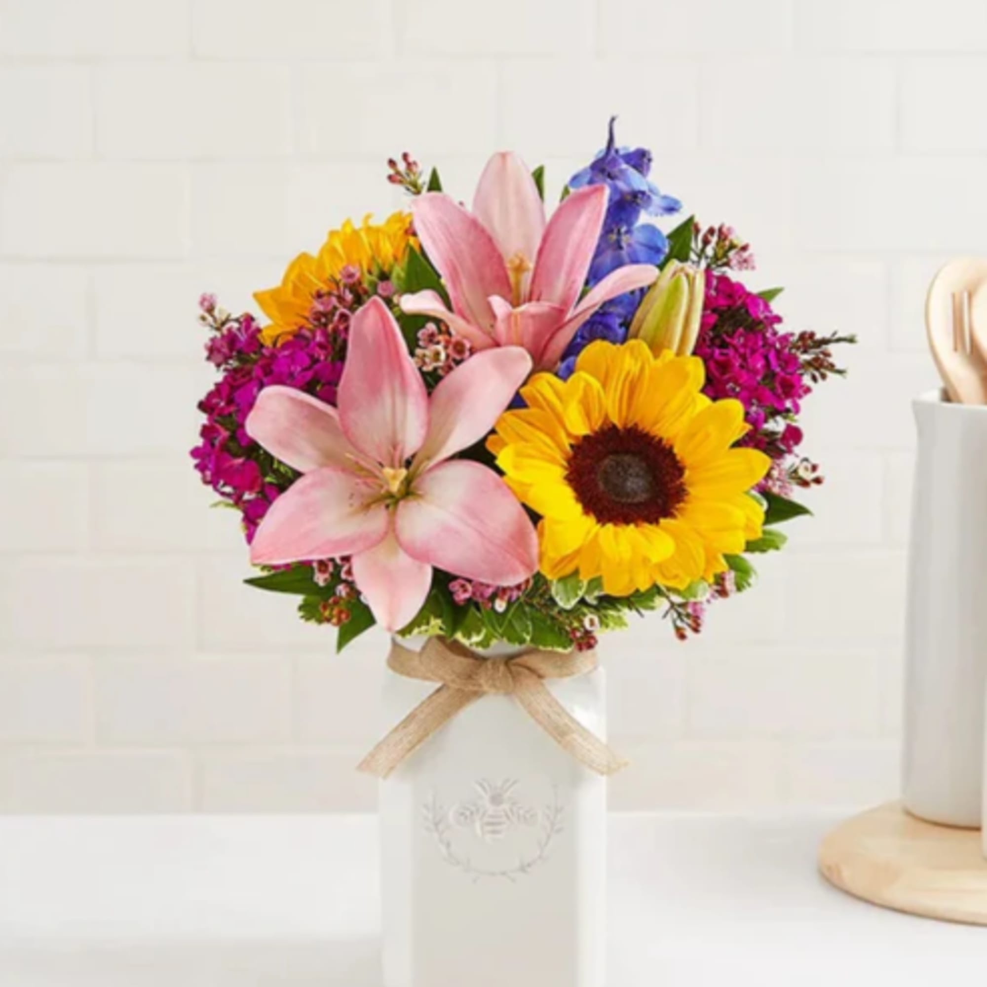 Bouquet of pink lilies and yellow sunflowers in a white vase