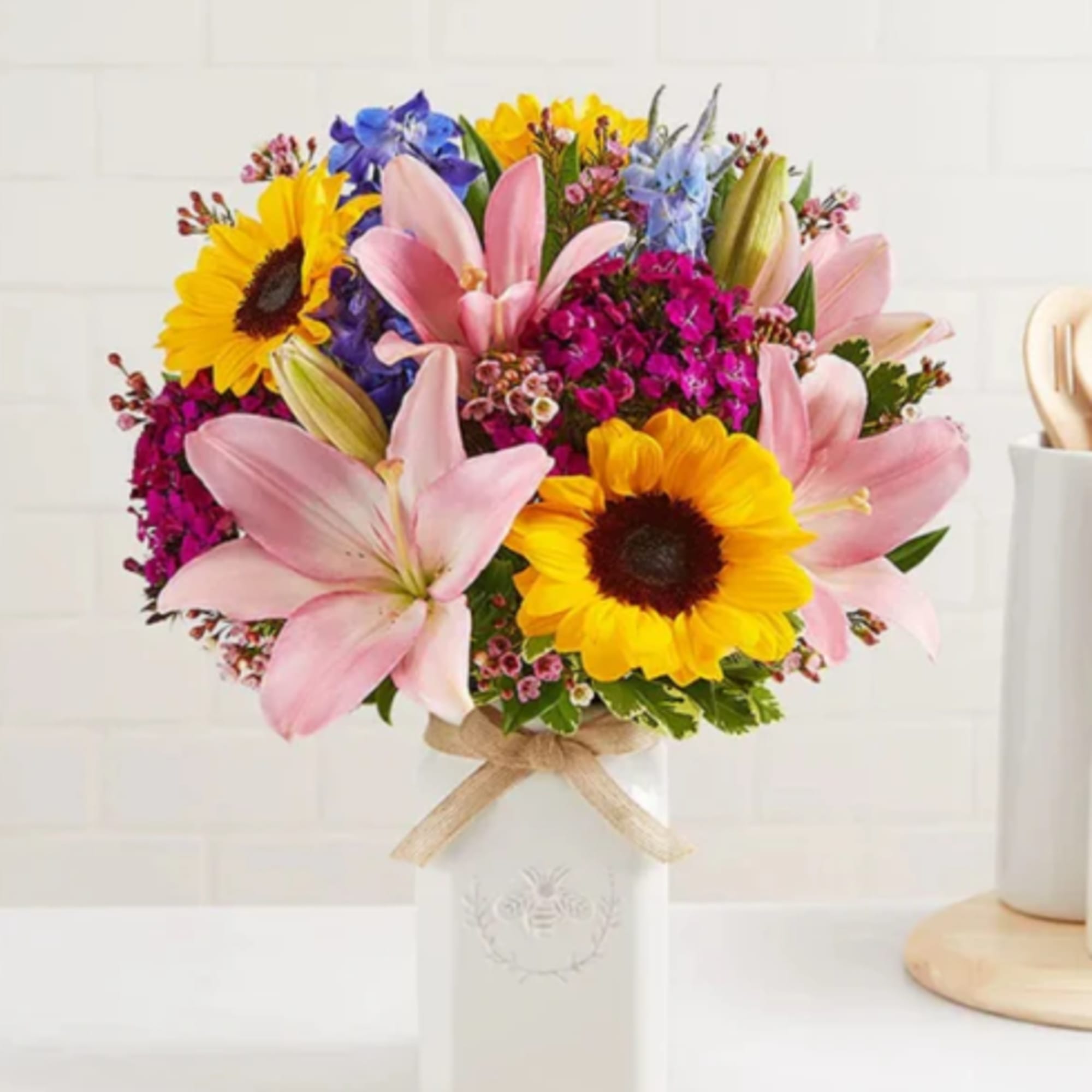 Bouquet of pink lilies and sunflowers in a white vase