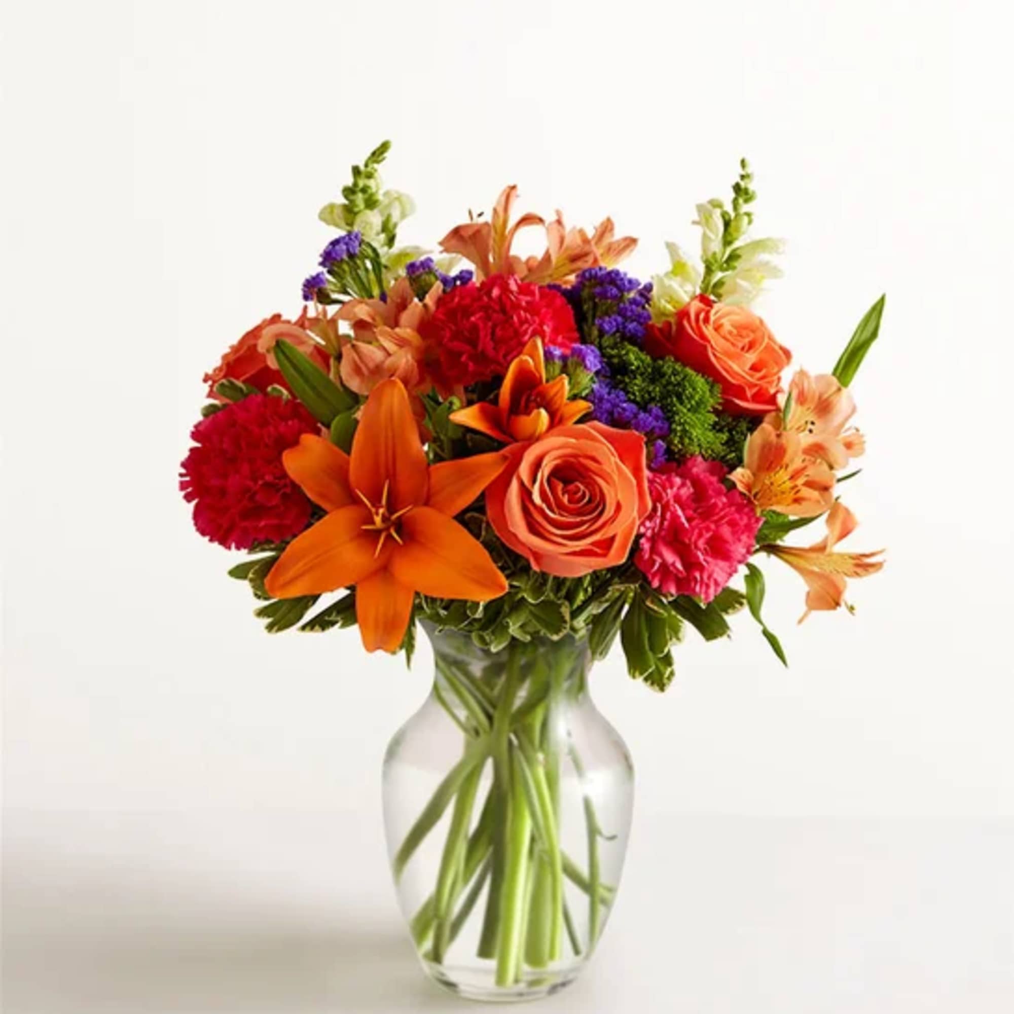 Orange and pink mixed bouquet in a clear glass vase