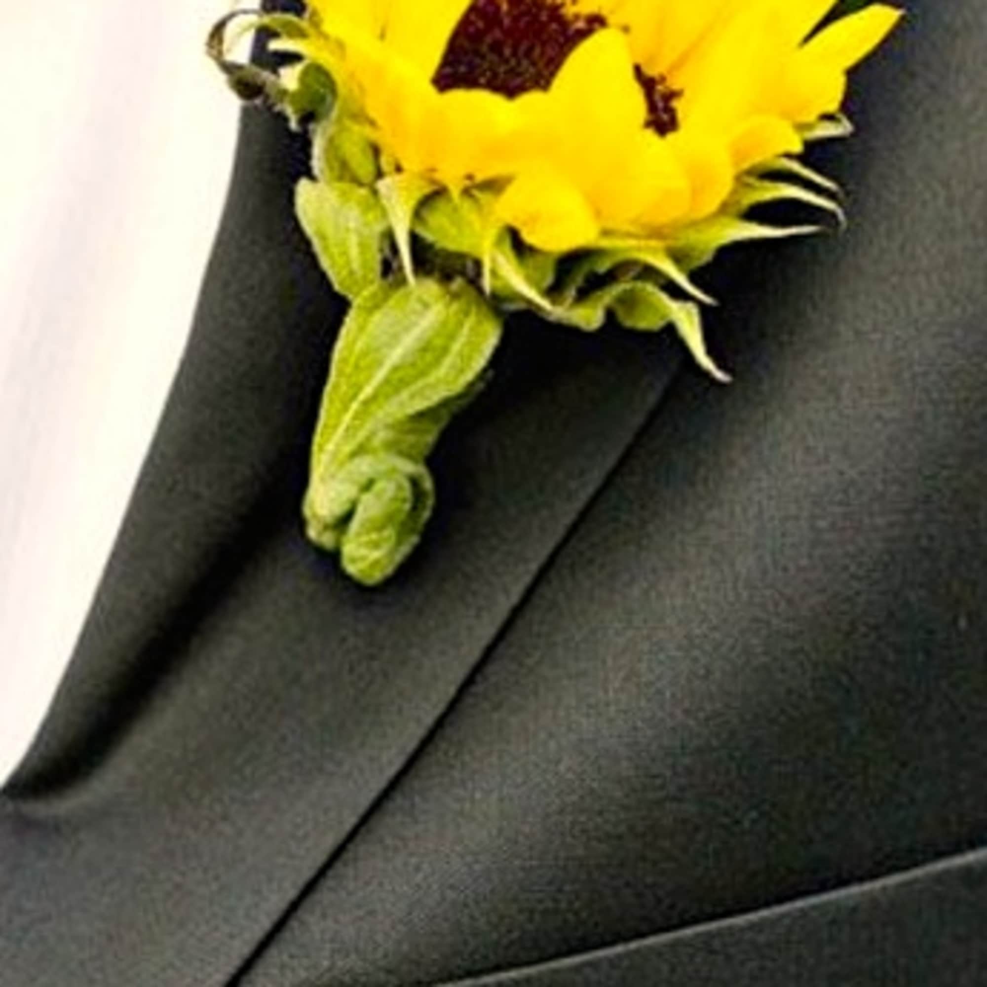 Yellow sunflower boutonniere pinned to a black suit jacket