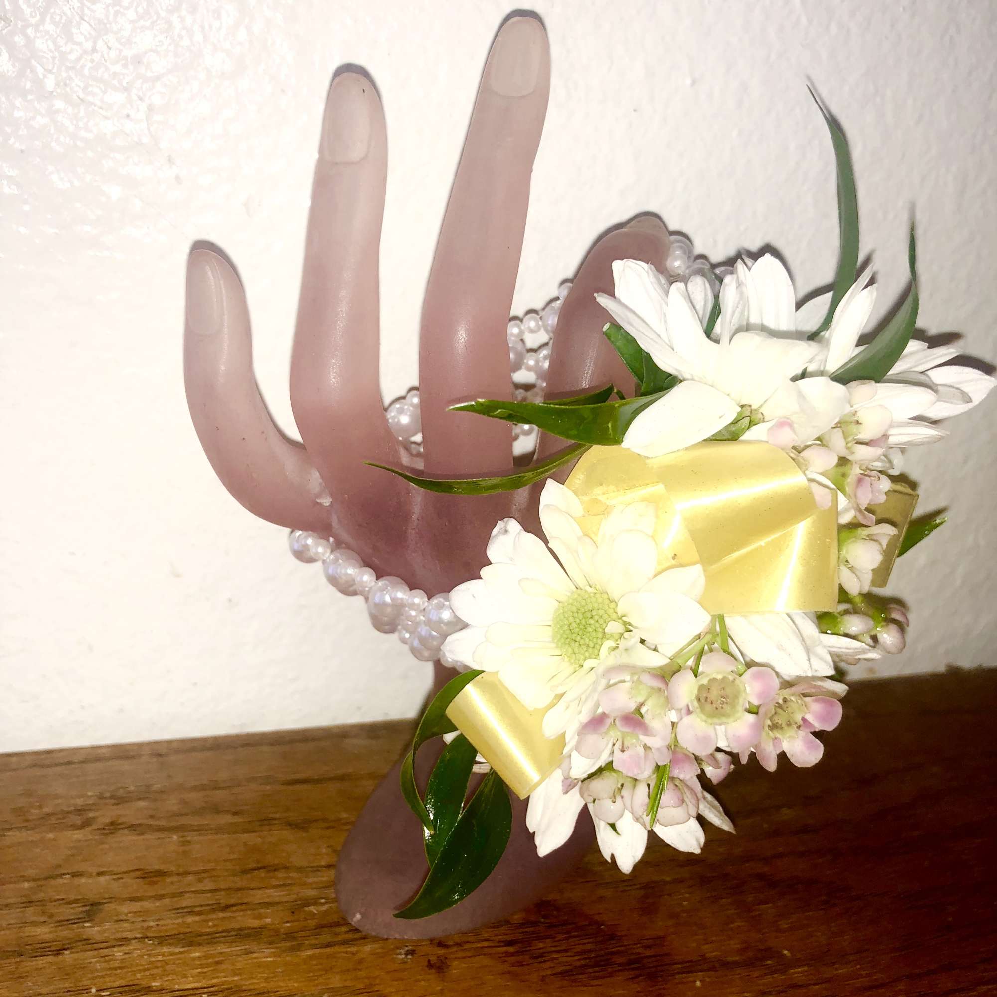 White daisy corsage with yellow ribbon on a pearl bracelet