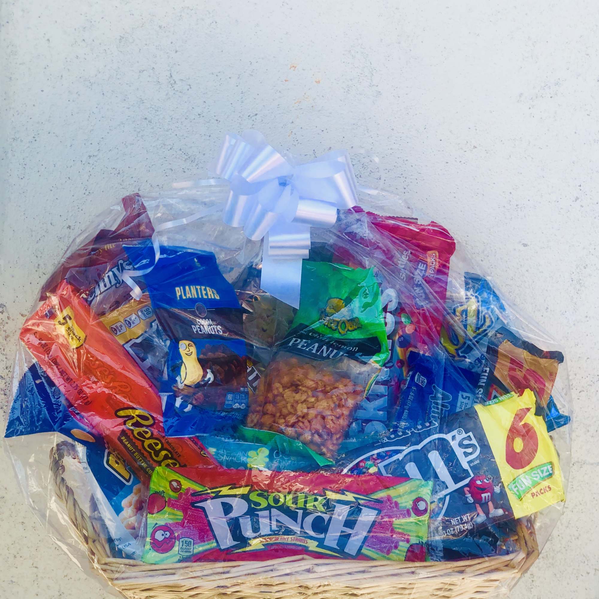 Basket of assorted snack bags wrapped in clear cellophane with a white bow