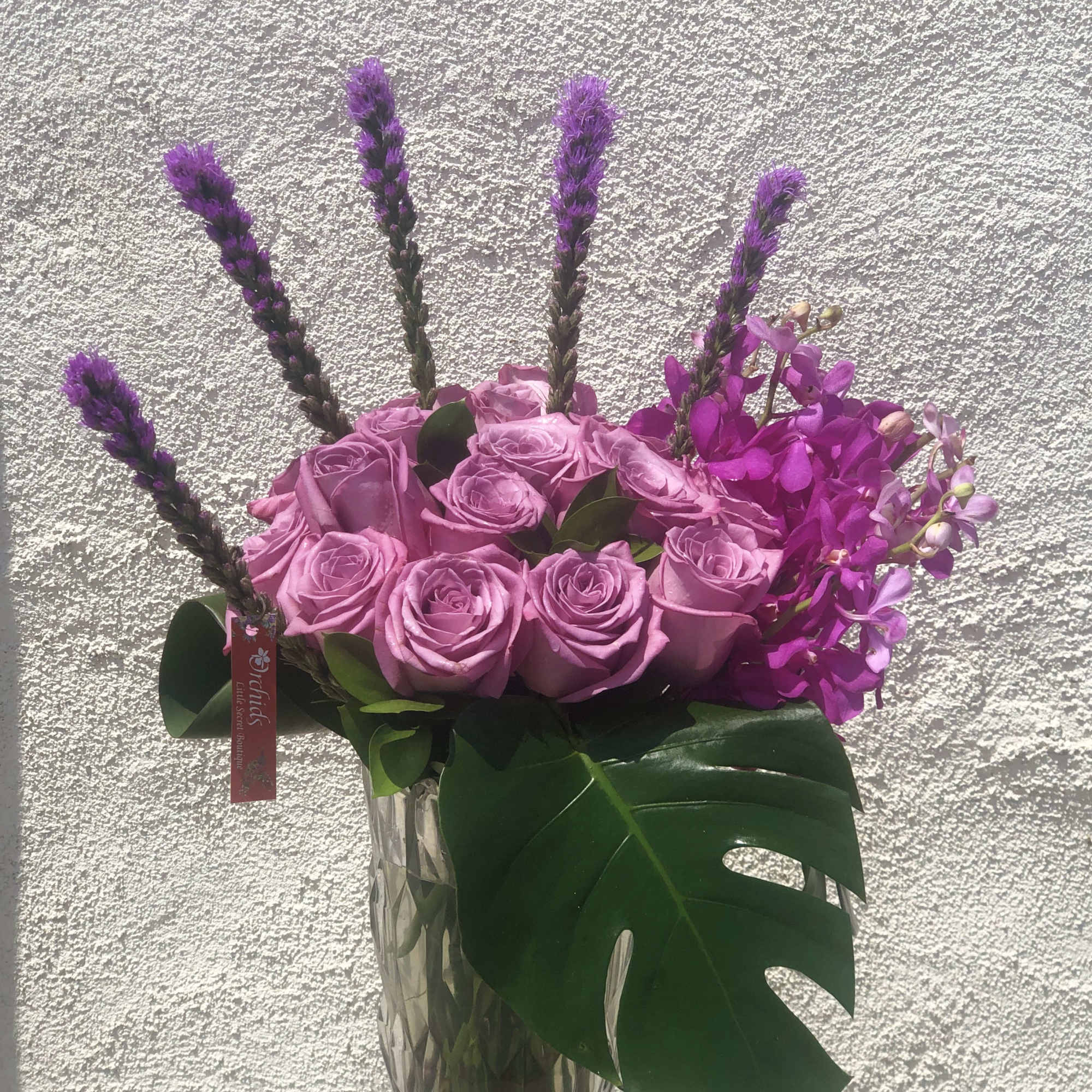 Pink roses and purple orchids in a clear glass vase