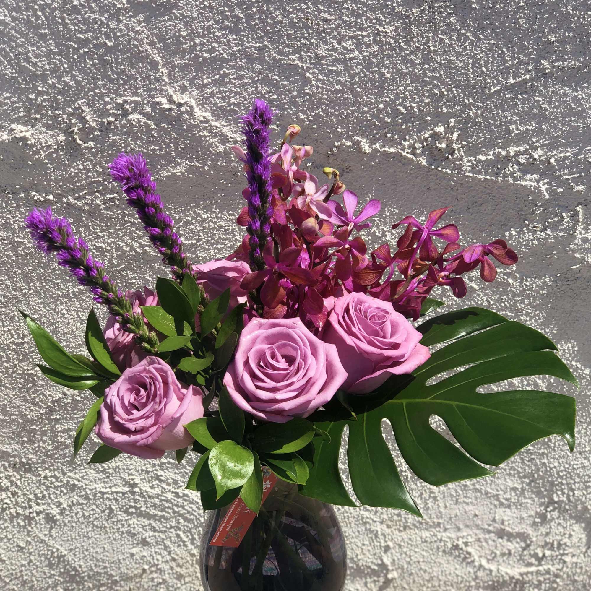 Pink roses and purple flowers in a dark glass vase