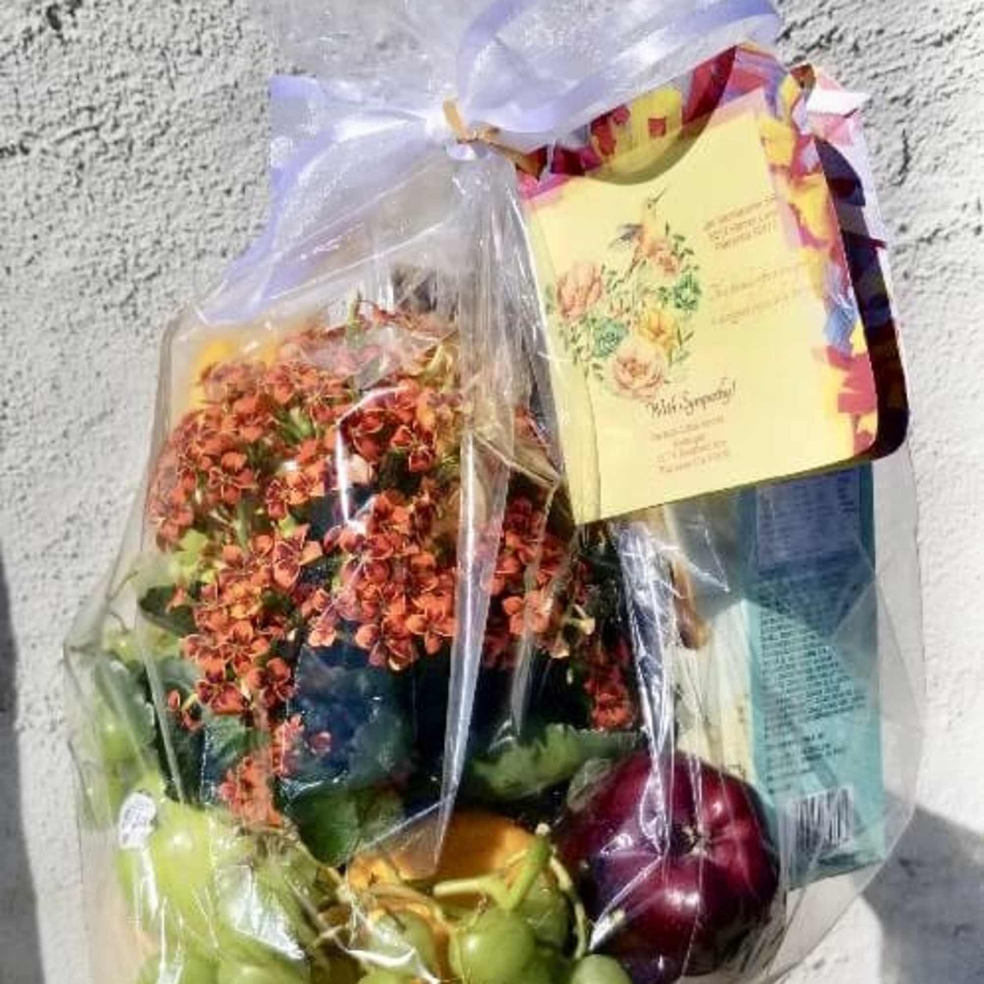 Wrapped gift basket with flowers, grapes, and a card
