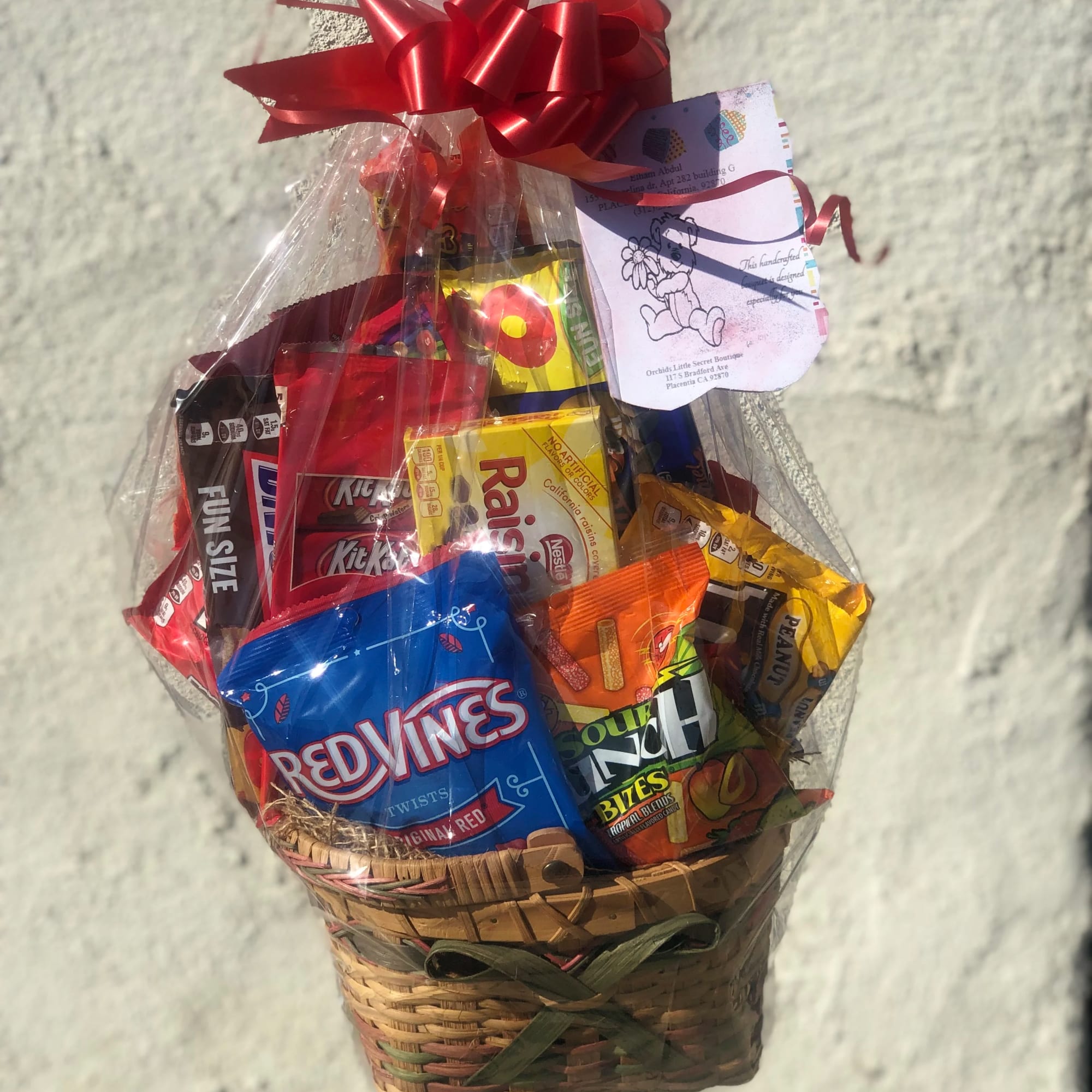 Basket of assorted candy wrapped in clear cellophane with a red bow