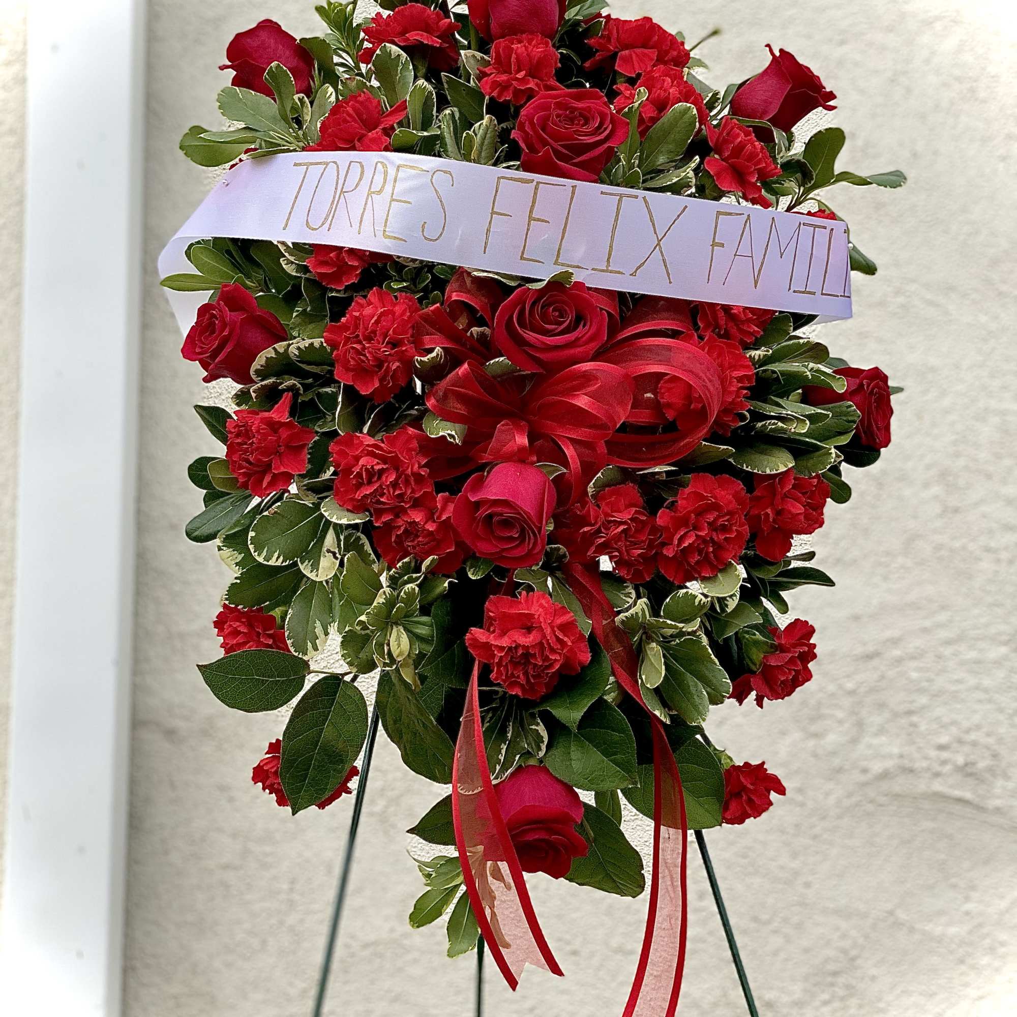 Red rose and carnation standing spray with a memorial ribbon