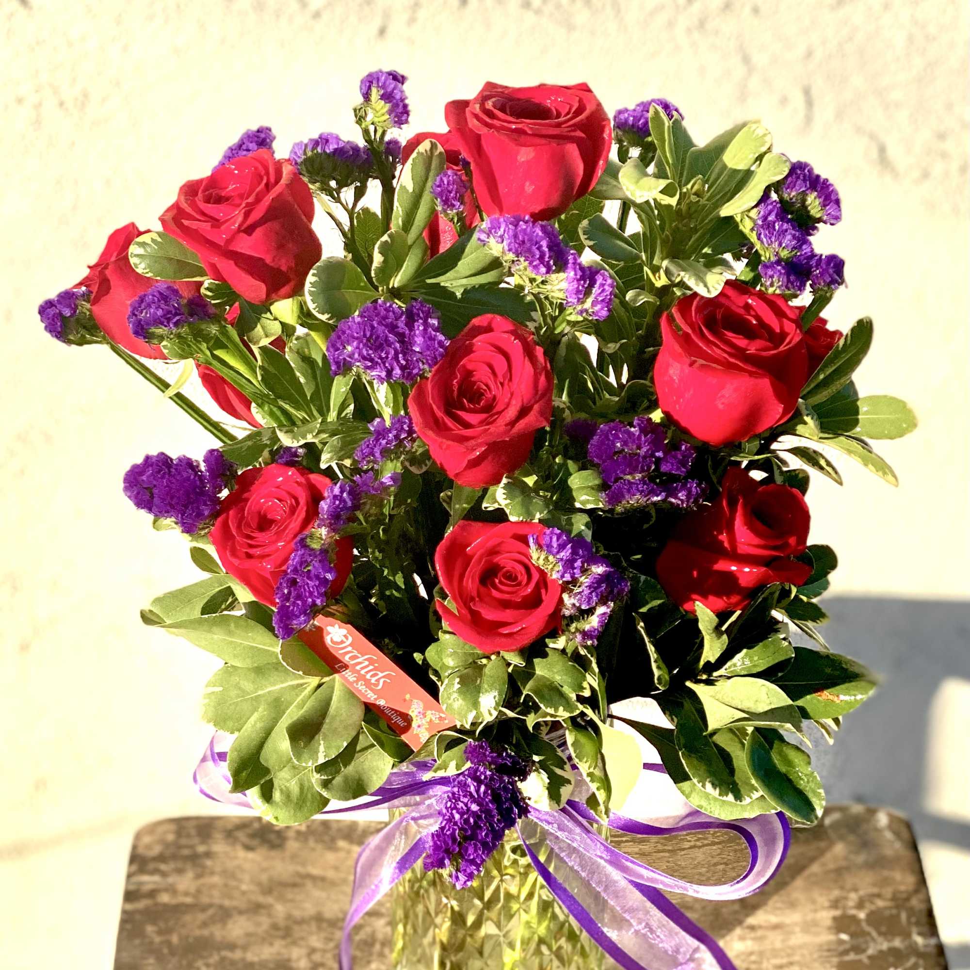 Bouquet of red roses and purple filler flowers in a glass vase