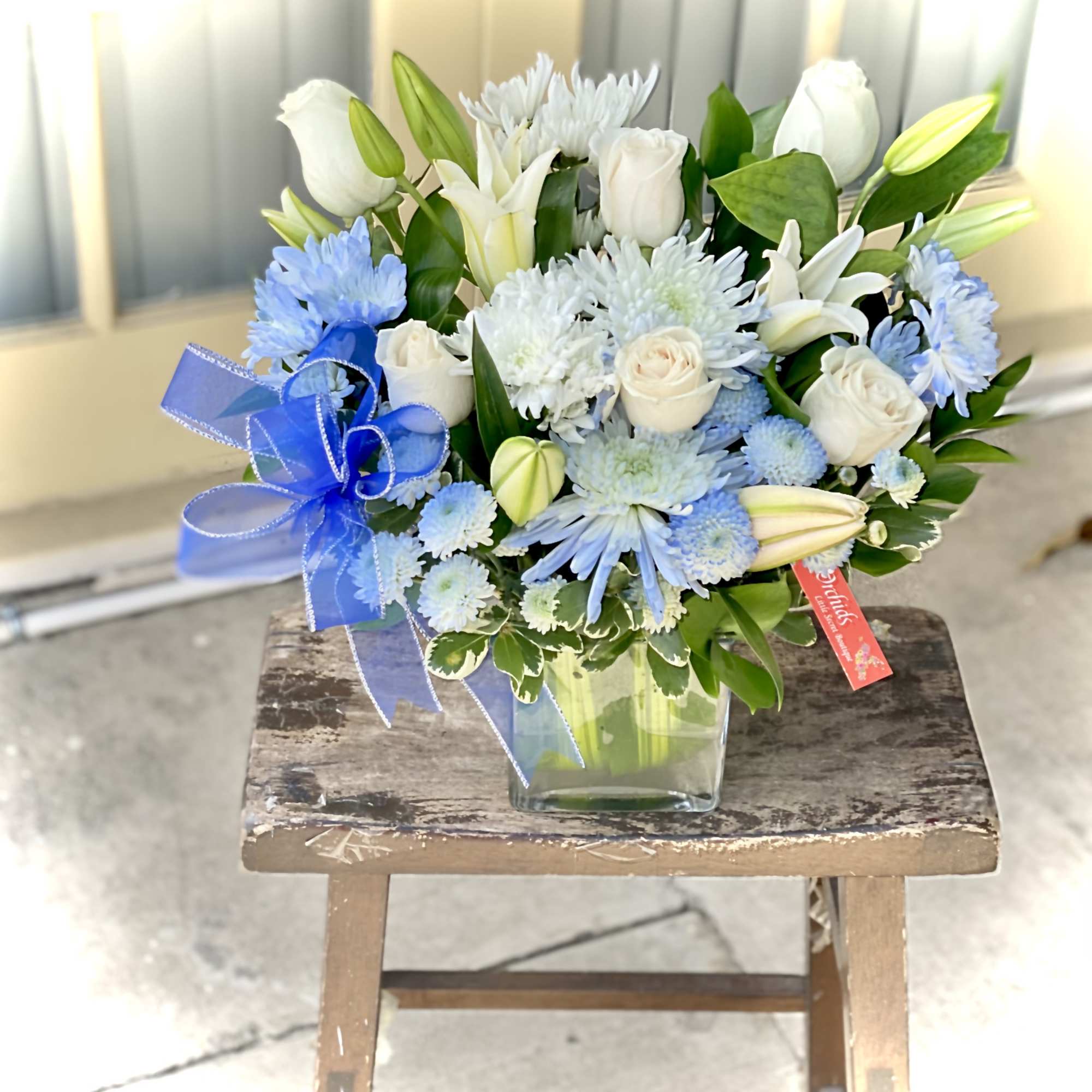 Blue and white bouquet in a clear glass vase with a blue ribbon