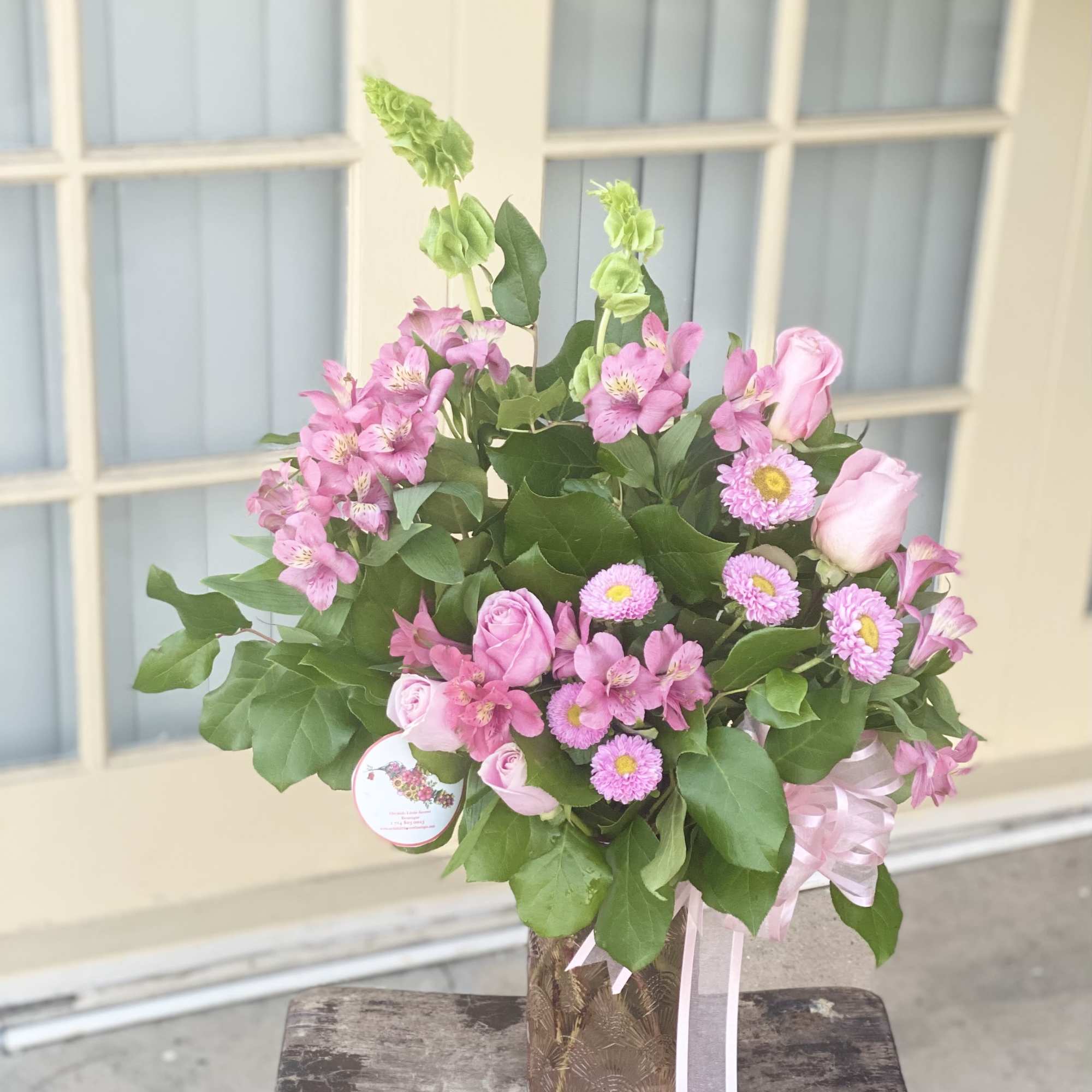 Pink roses and alstroemeria in a decorative vase with ribbon