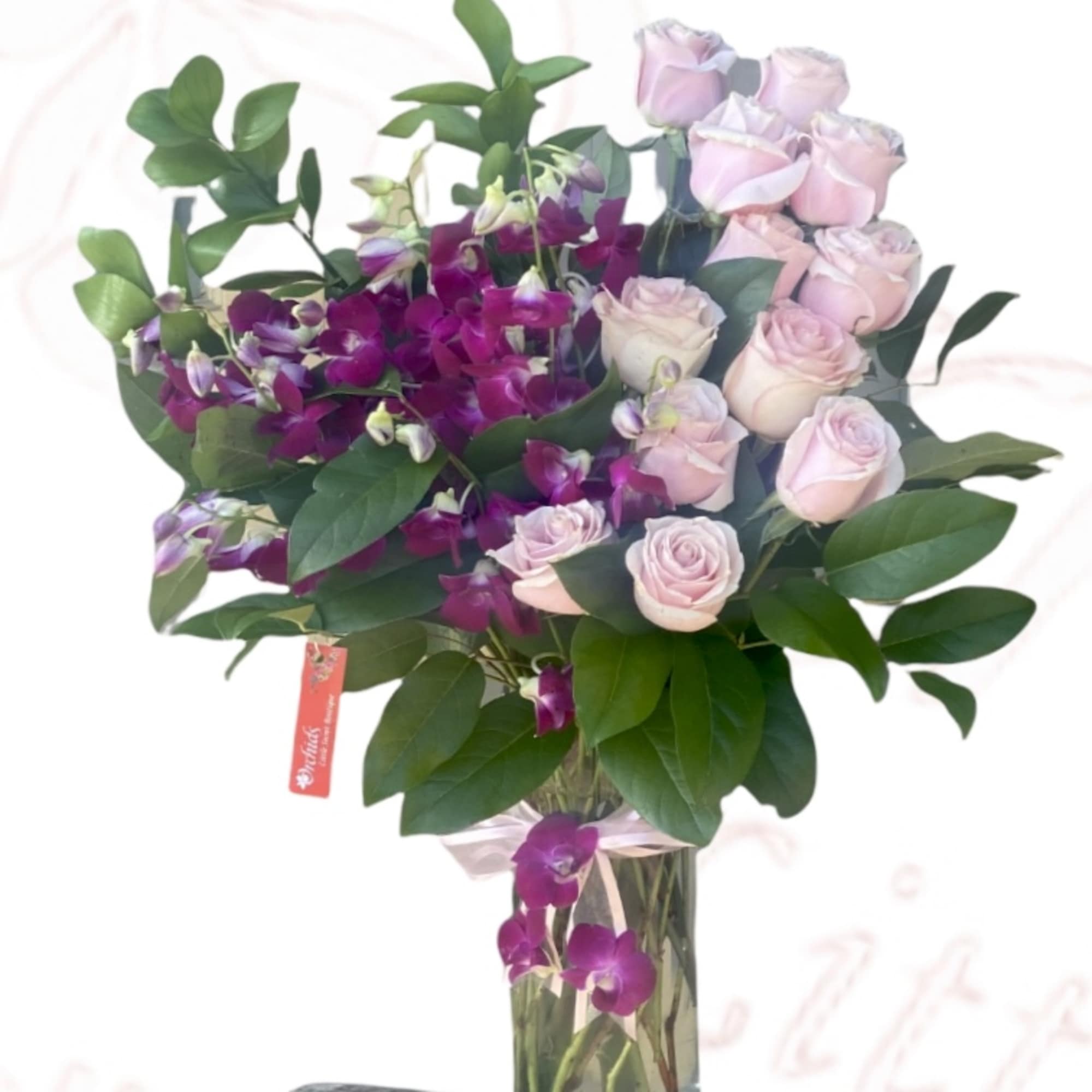 Pink roses and purple orchids in a tall glass vase