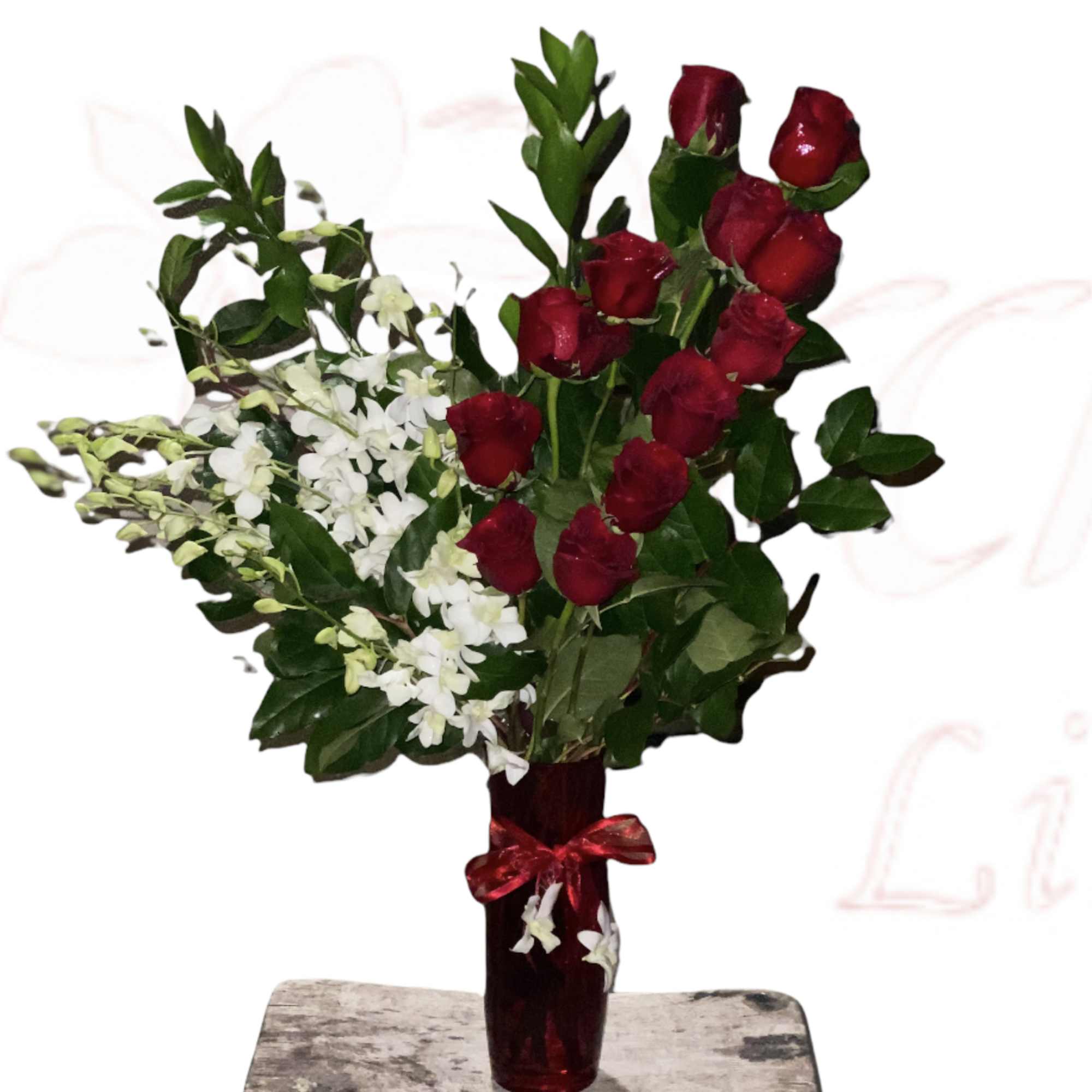 Red roses and white flowers in a red glass vase with a ribbon