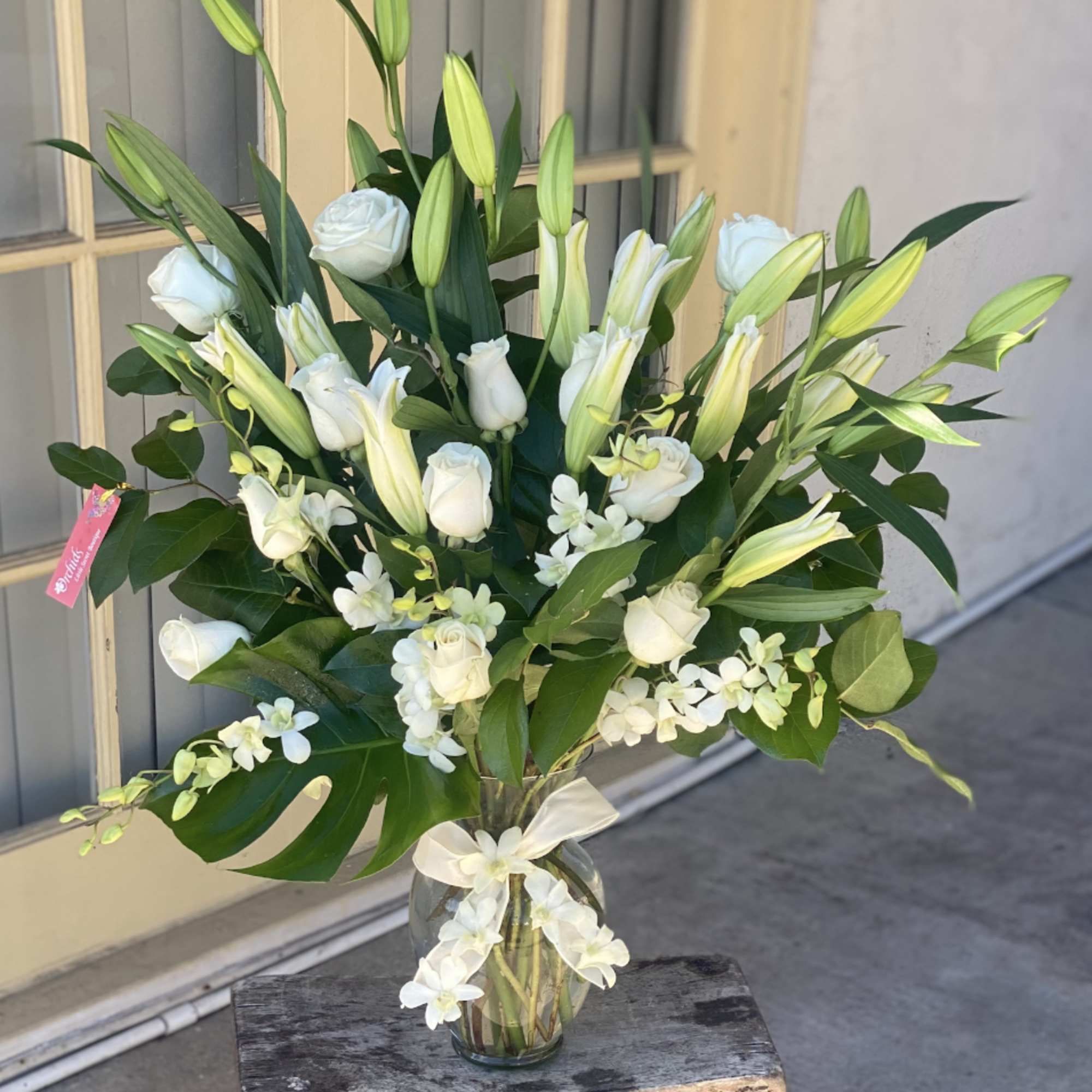 White roses and lilies arranged in a clear glass vase