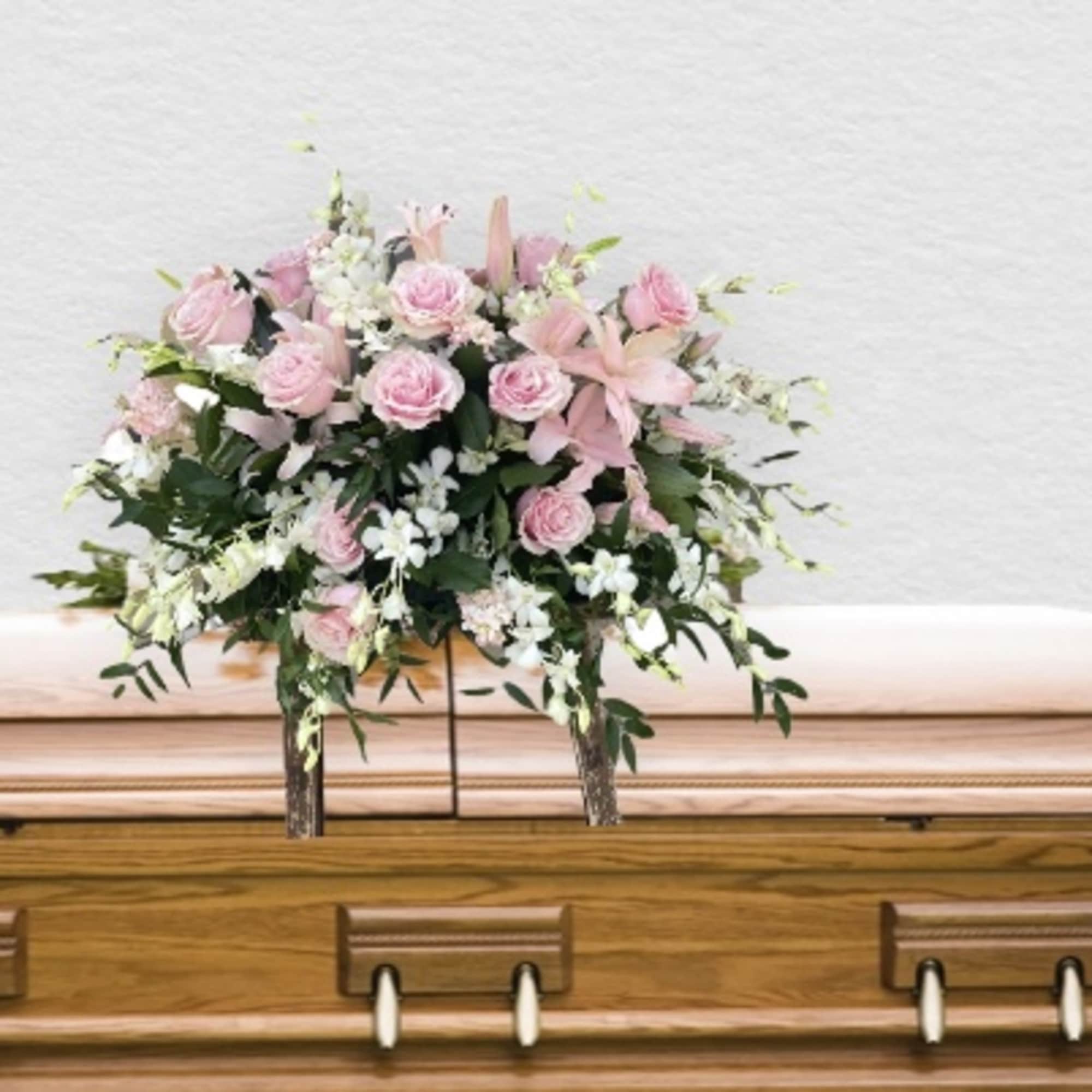 Pink and white floral spray on a wooden casket