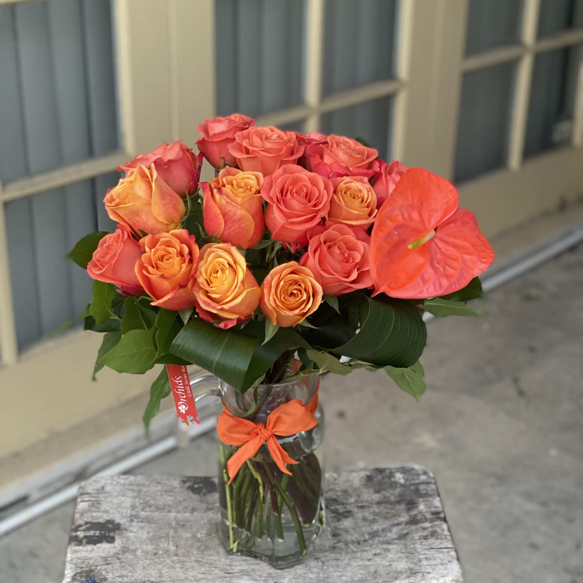 Bouquet of orange and pink roses in a clear glass vase