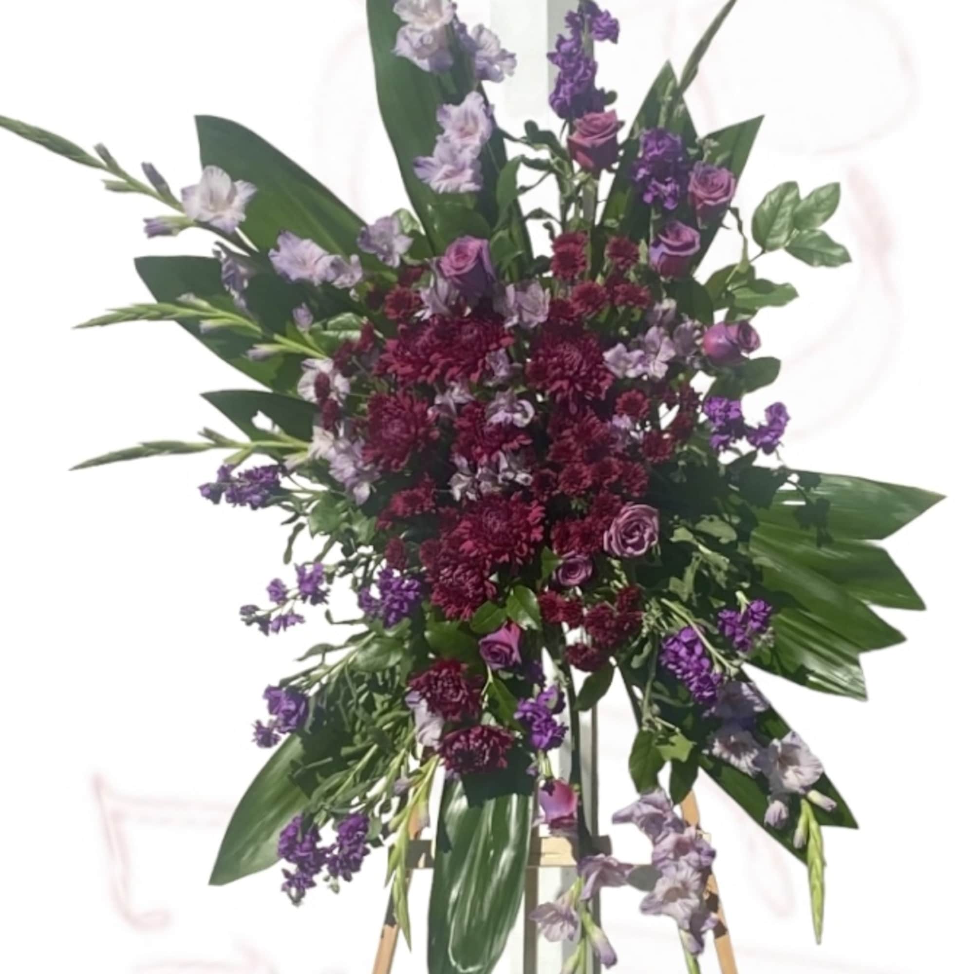 Standing floral spray with purple and burgundy flowers on an easel