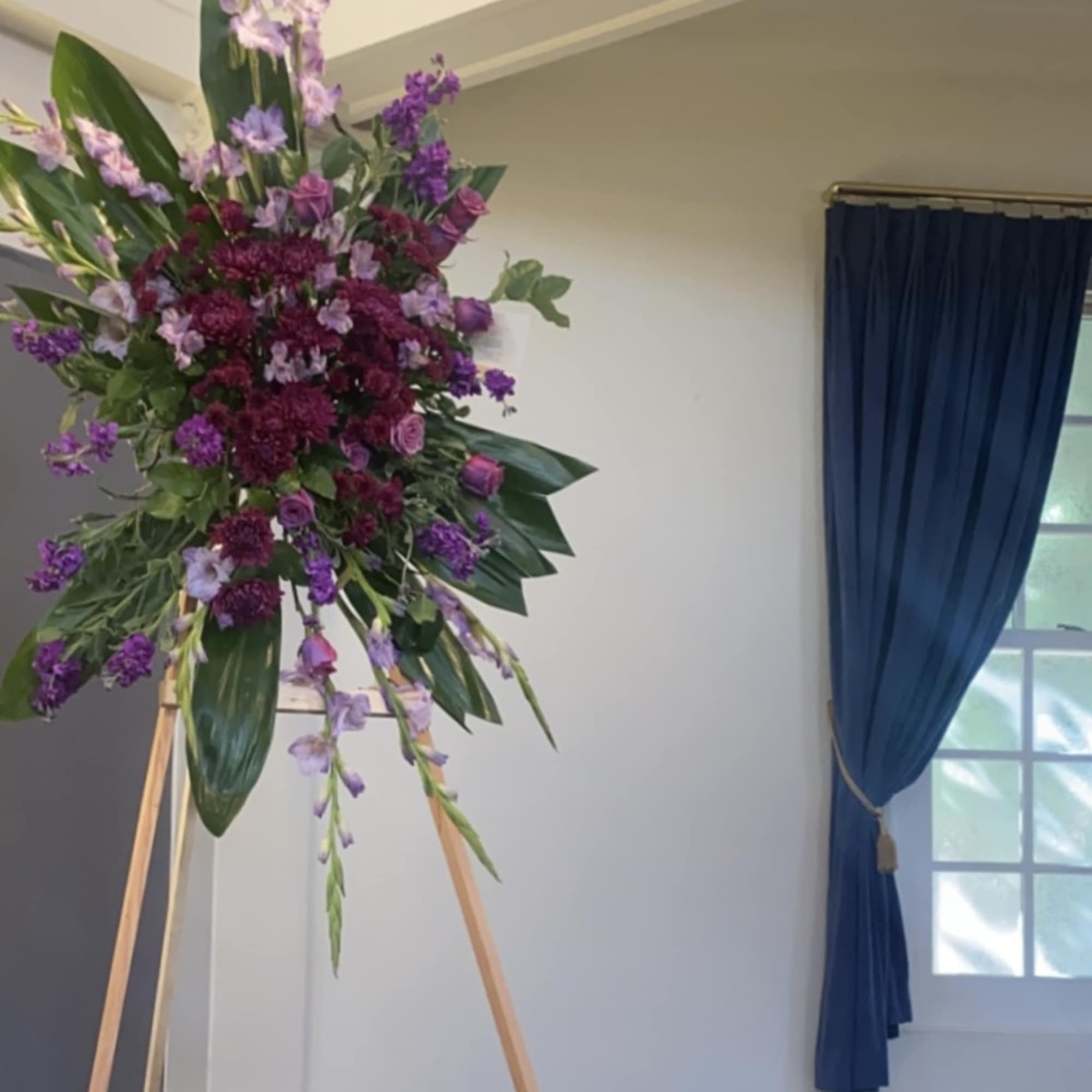 Large purple floral arrangement on a wooden easel