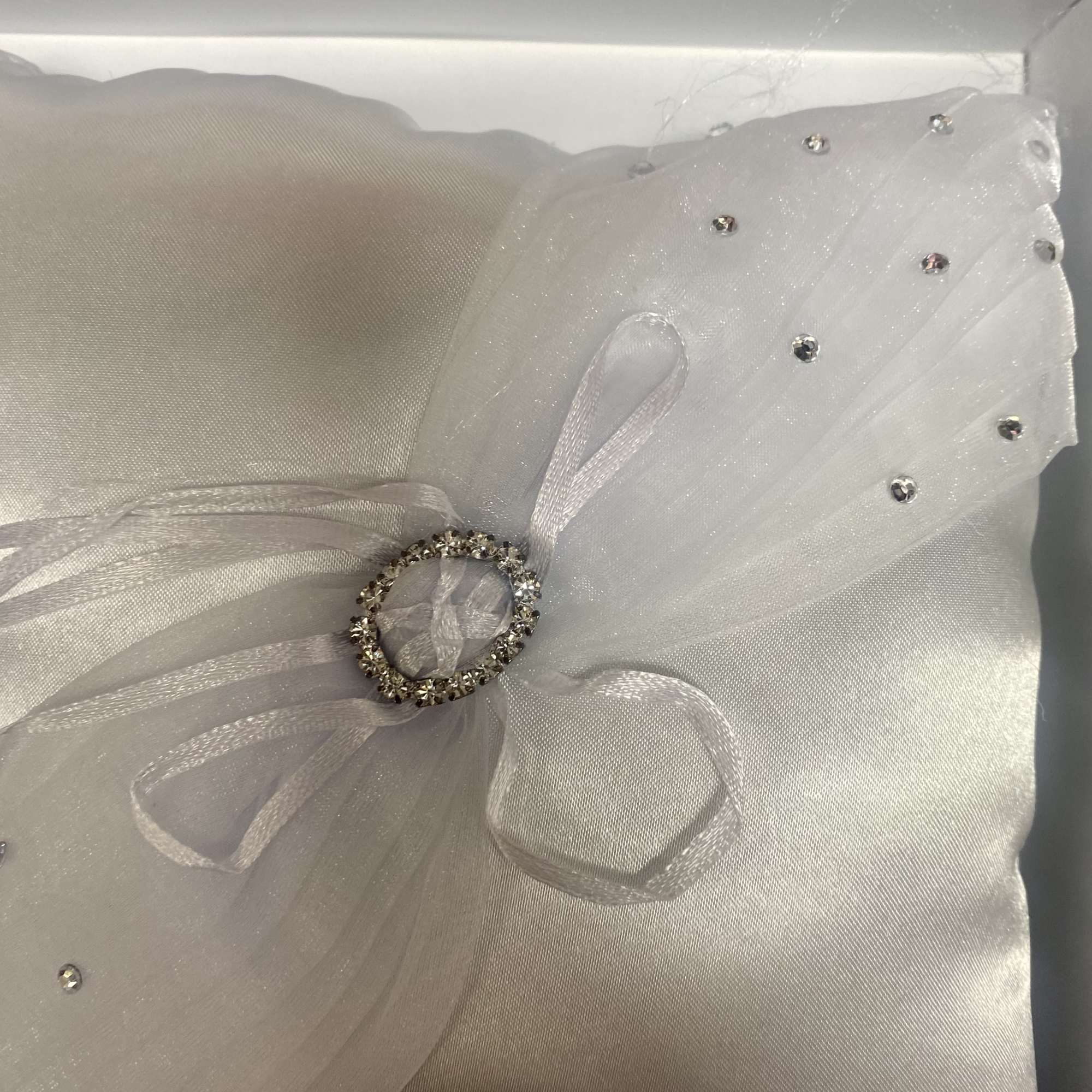 White satin pillow with sheer tulle bow and rhinestone accents