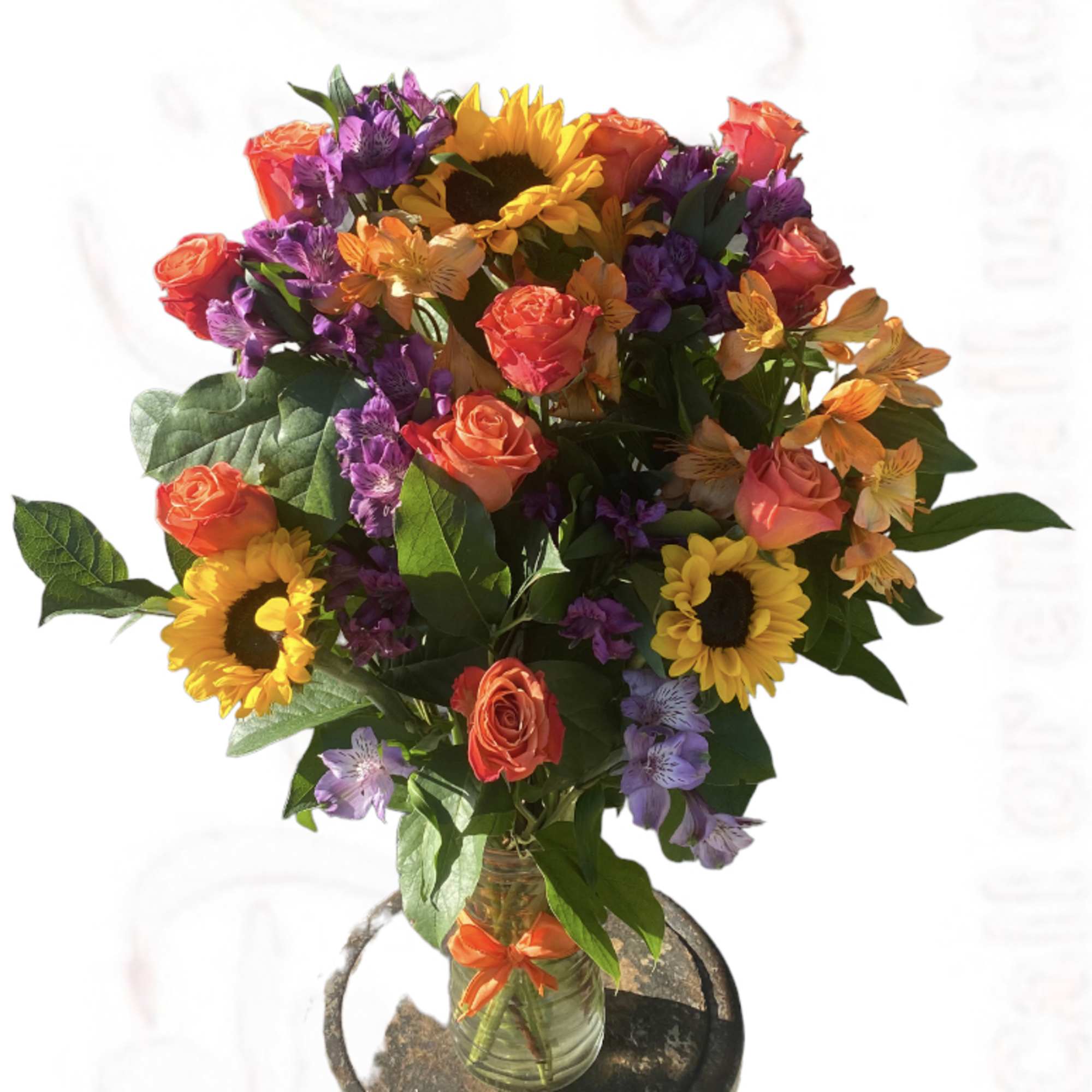 Bouquet of roses, sunflowers, and purple flowers in a glass vase