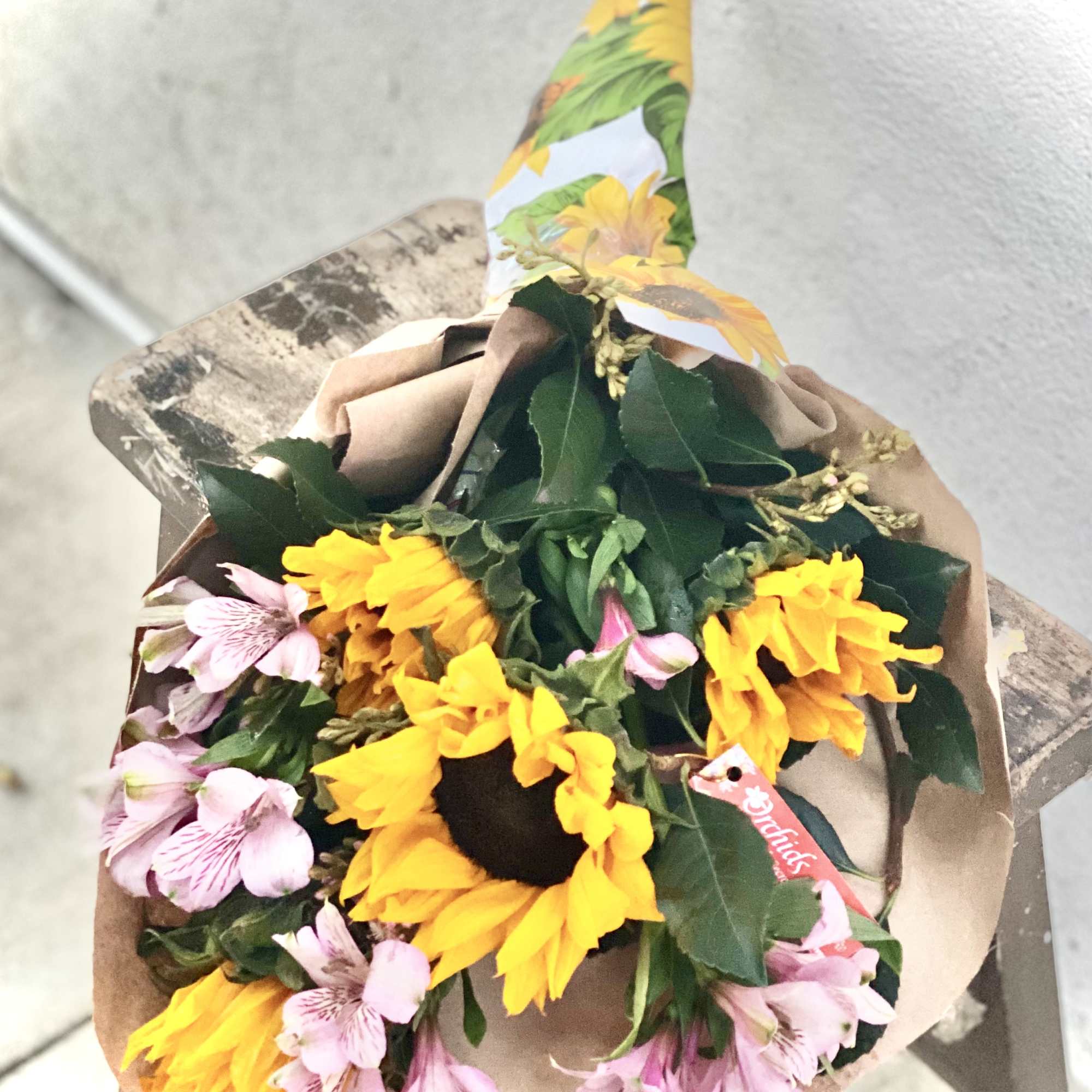 Bouquet of yellow sunflowers and pink alstroemeria wrapped in brown paper
