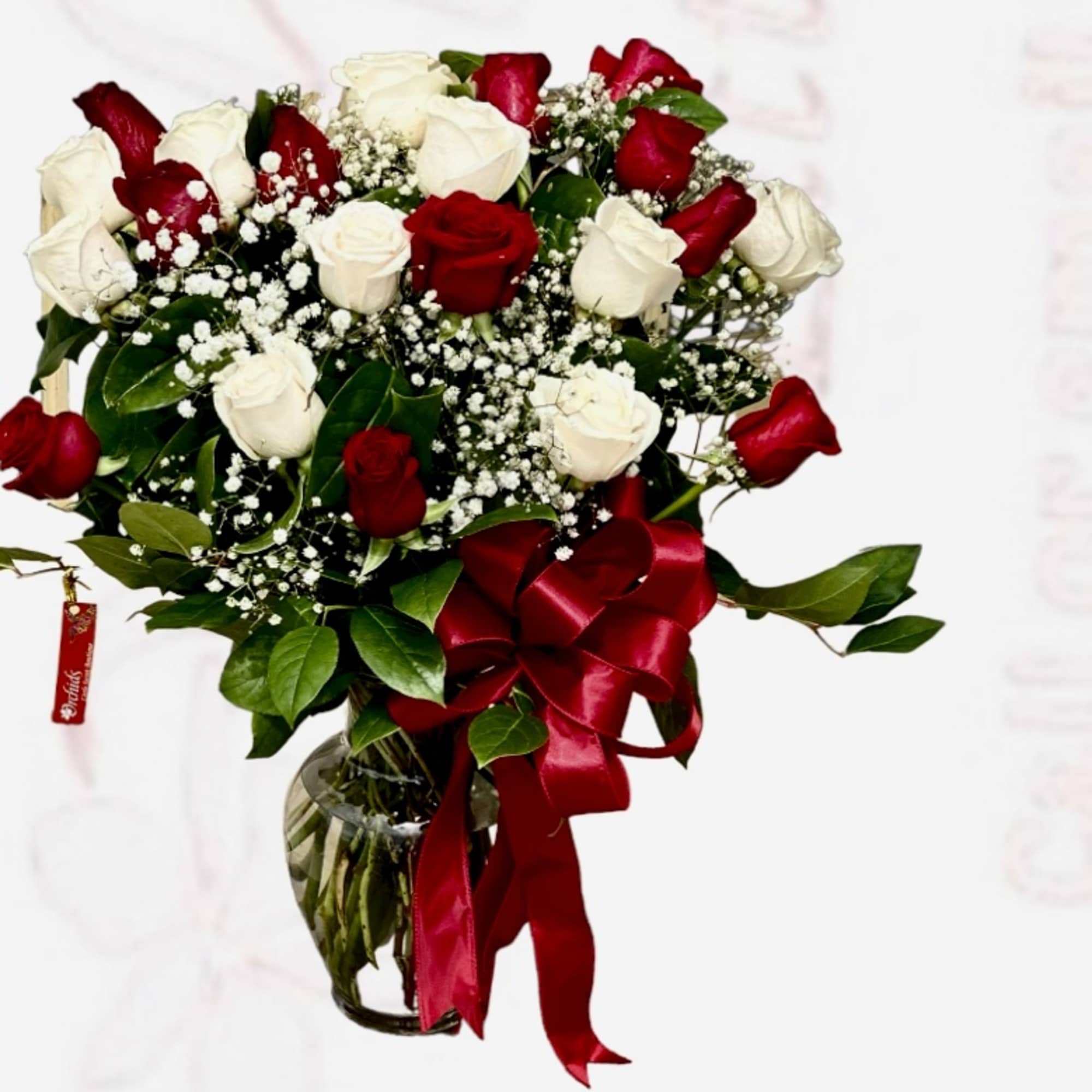 Bouquet of red and white roses in a glass vase with a red ribbon