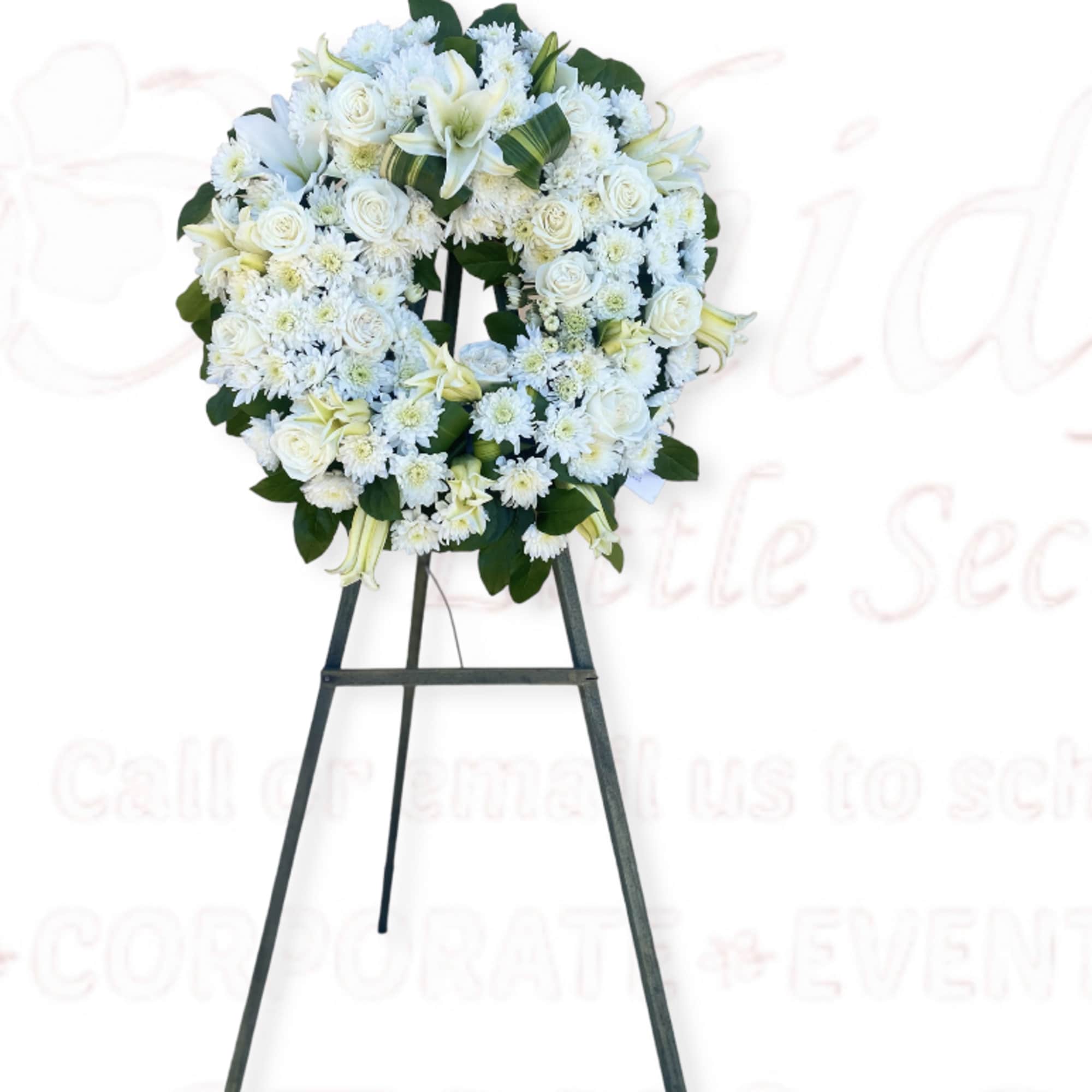 White floral wreath on a black easel stand