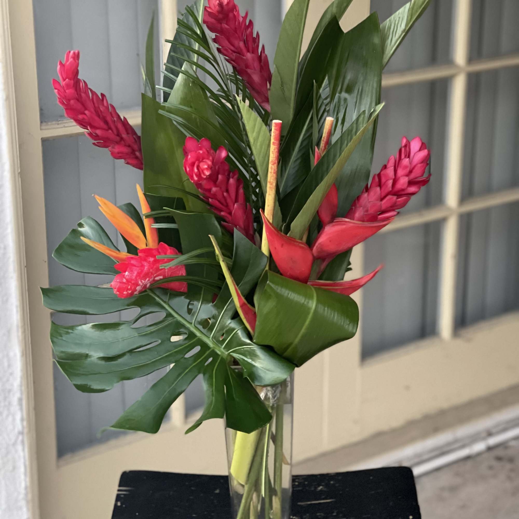 Tropical bouquet with pink flowers in a clear glass vase