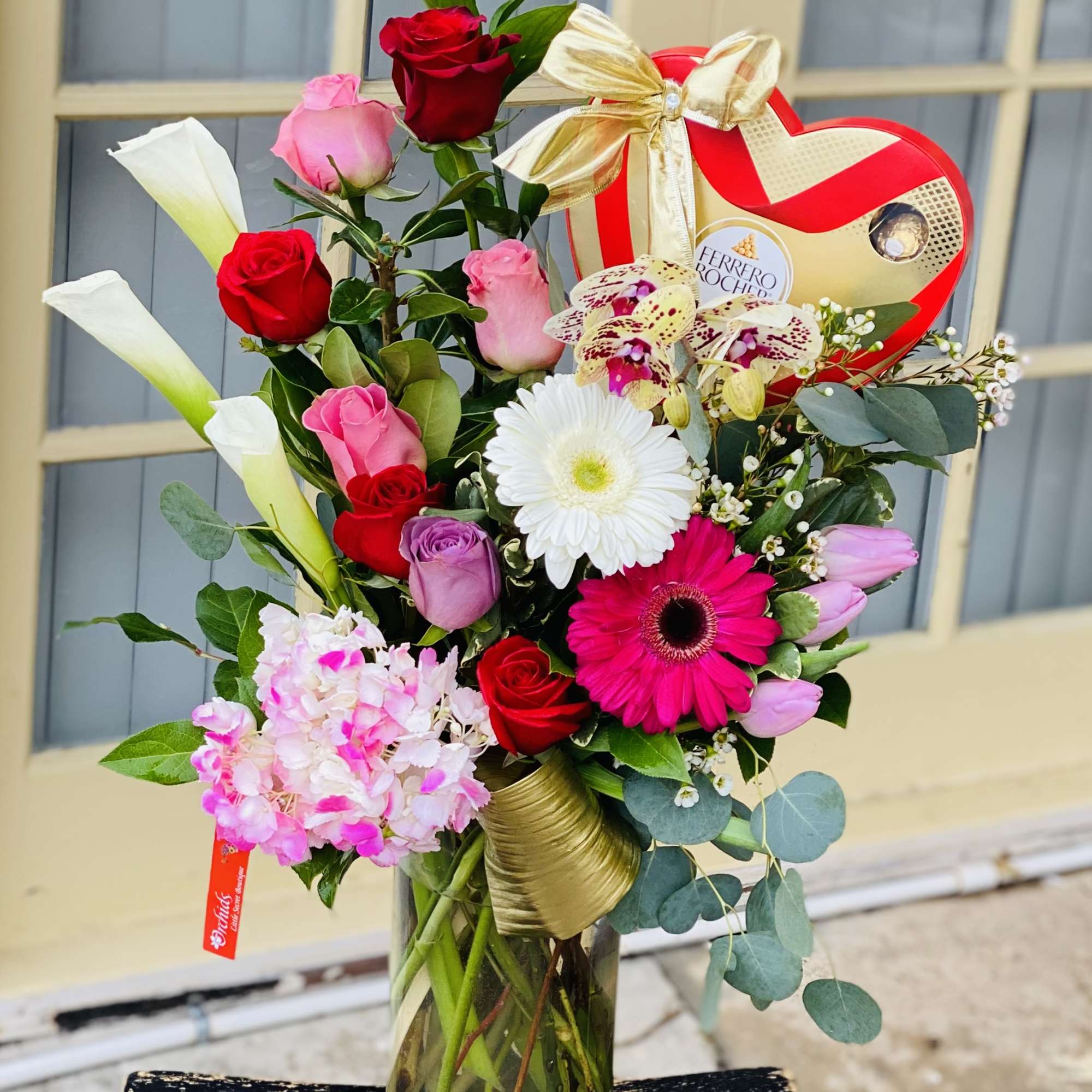 Mixed bouquet in a glass vase with roses, gerbera daisies, and orchids