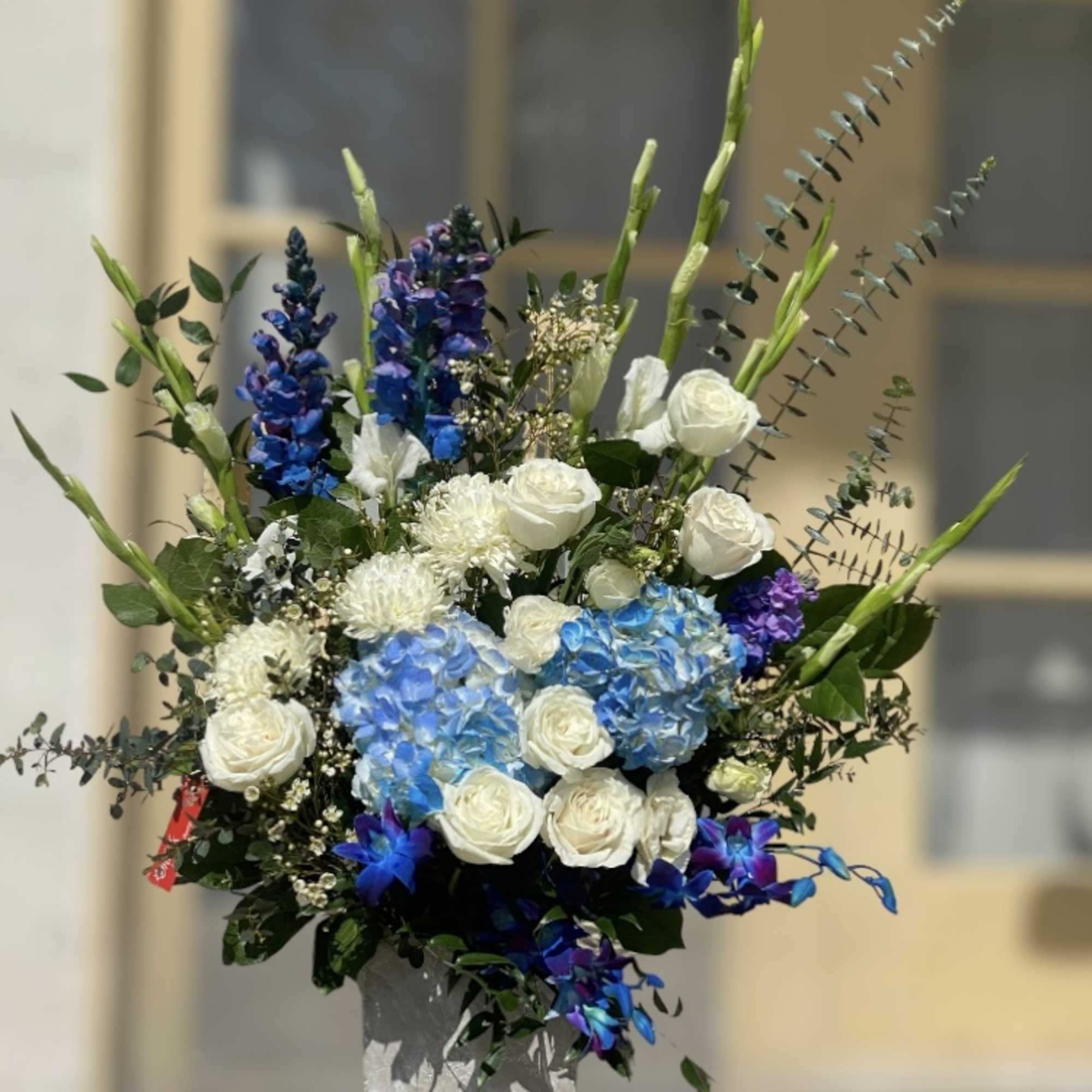 Tall bouquet of white roses, blue hydrangeas, and purple flowers in a vase