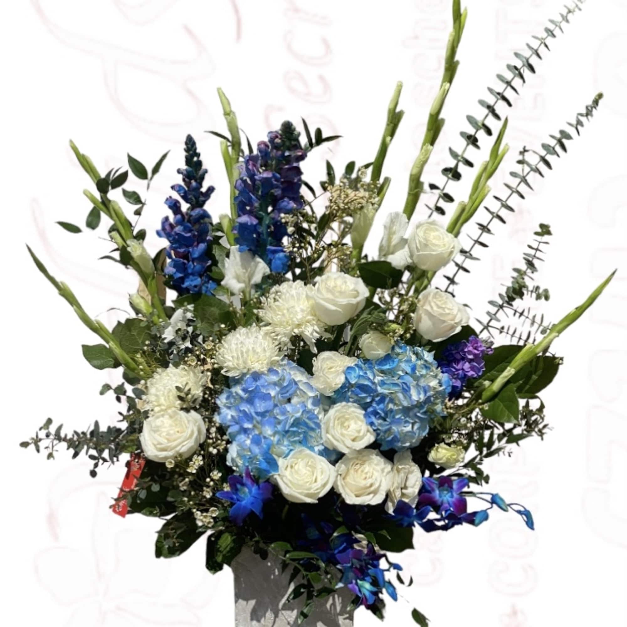 Tall floral arrangement with blue and white flowers in a square vase
