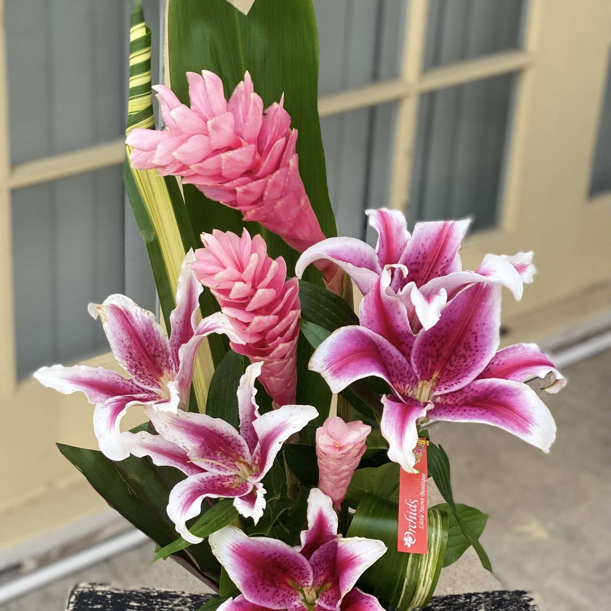 Pink lilies and ginger flowers arranged in a glass vase