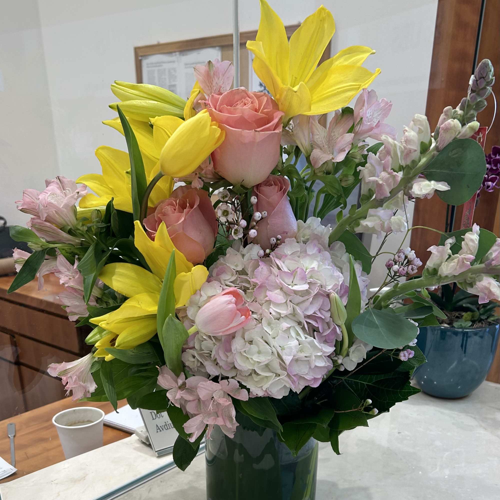 Pink roses and yellow lilies arranged in a glass vase