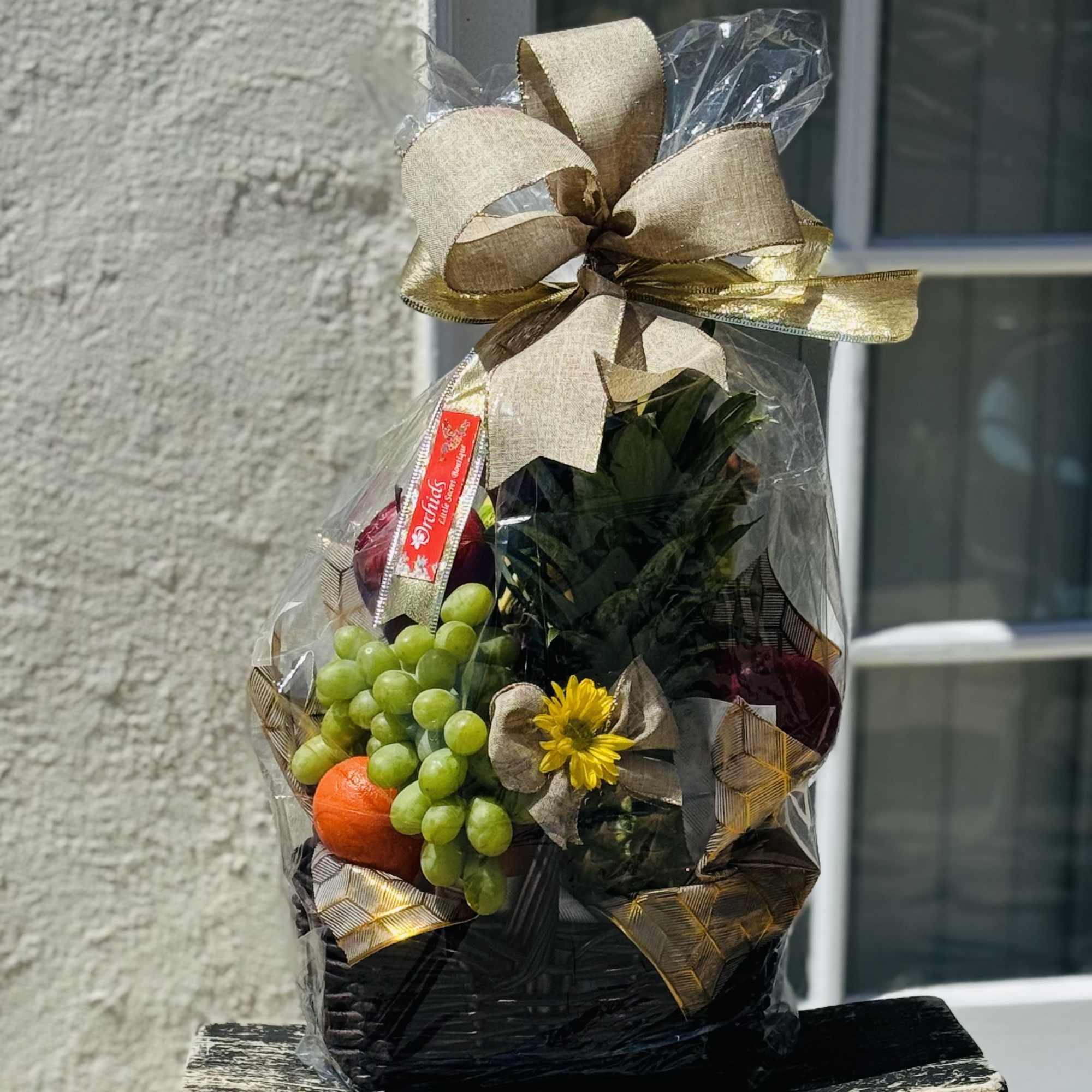 Gift basket with grapes, an orange, and a small yellow flower