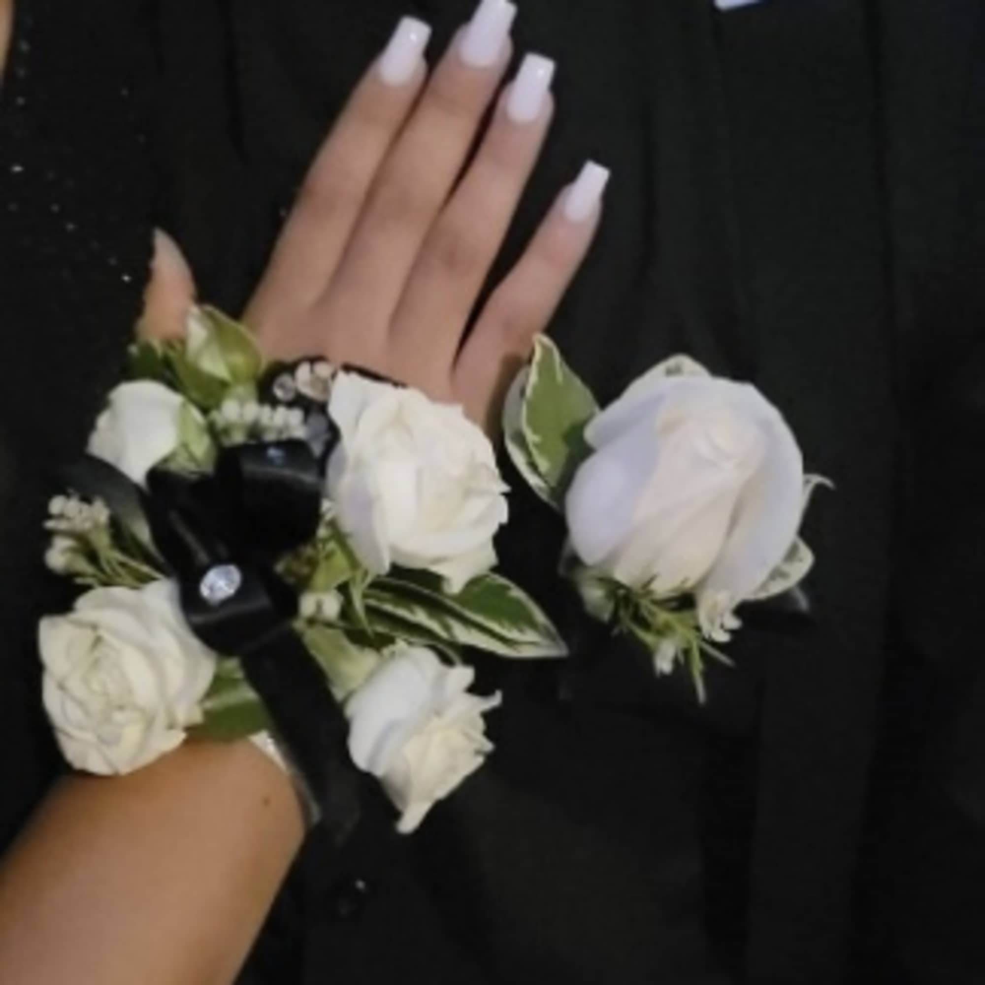 White rose corsage and boutonniere on a black outfit