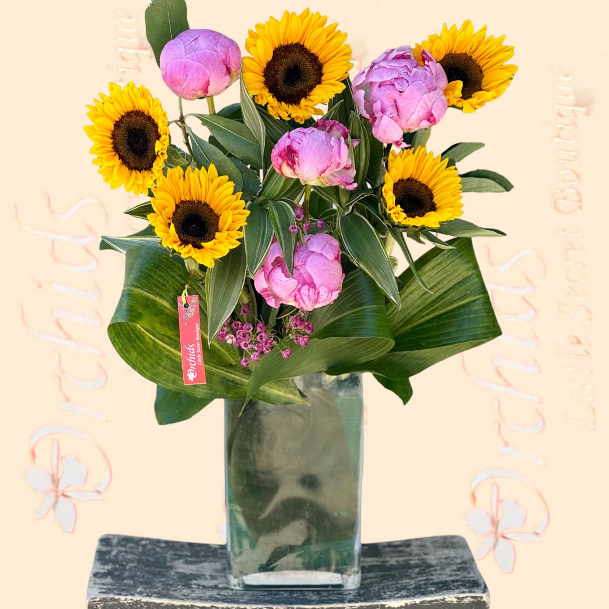 Sunflowers and pink peonies in a tall glass vase