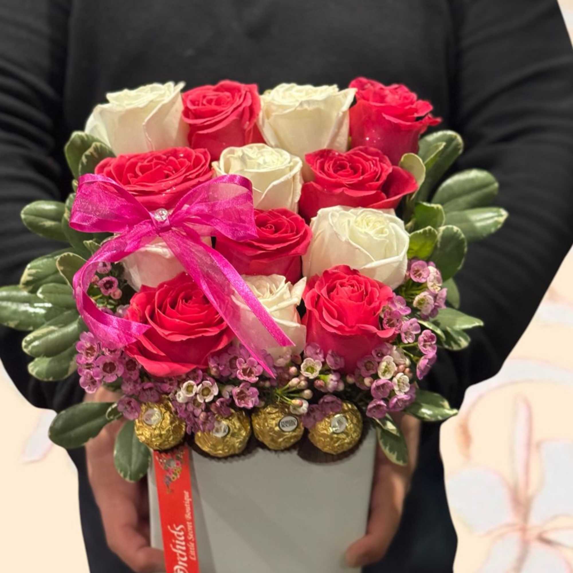 Box arrangement of red and white roses with a pink ribbon