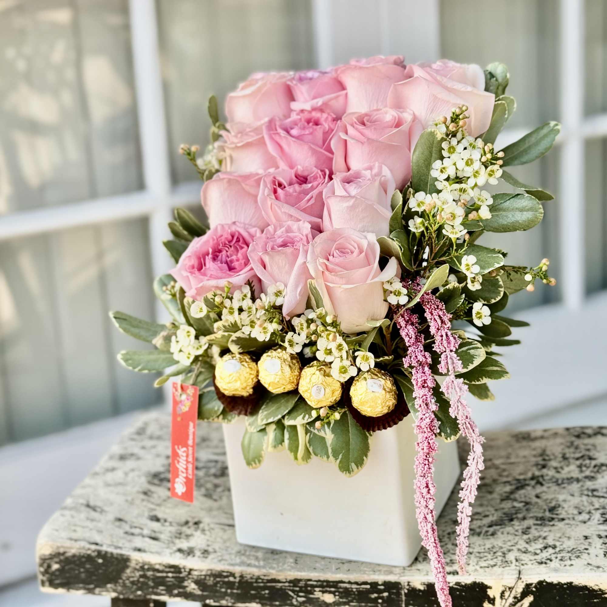 Pink roses arranged in a white square vase with small white filler flowers, photo 2 of 2