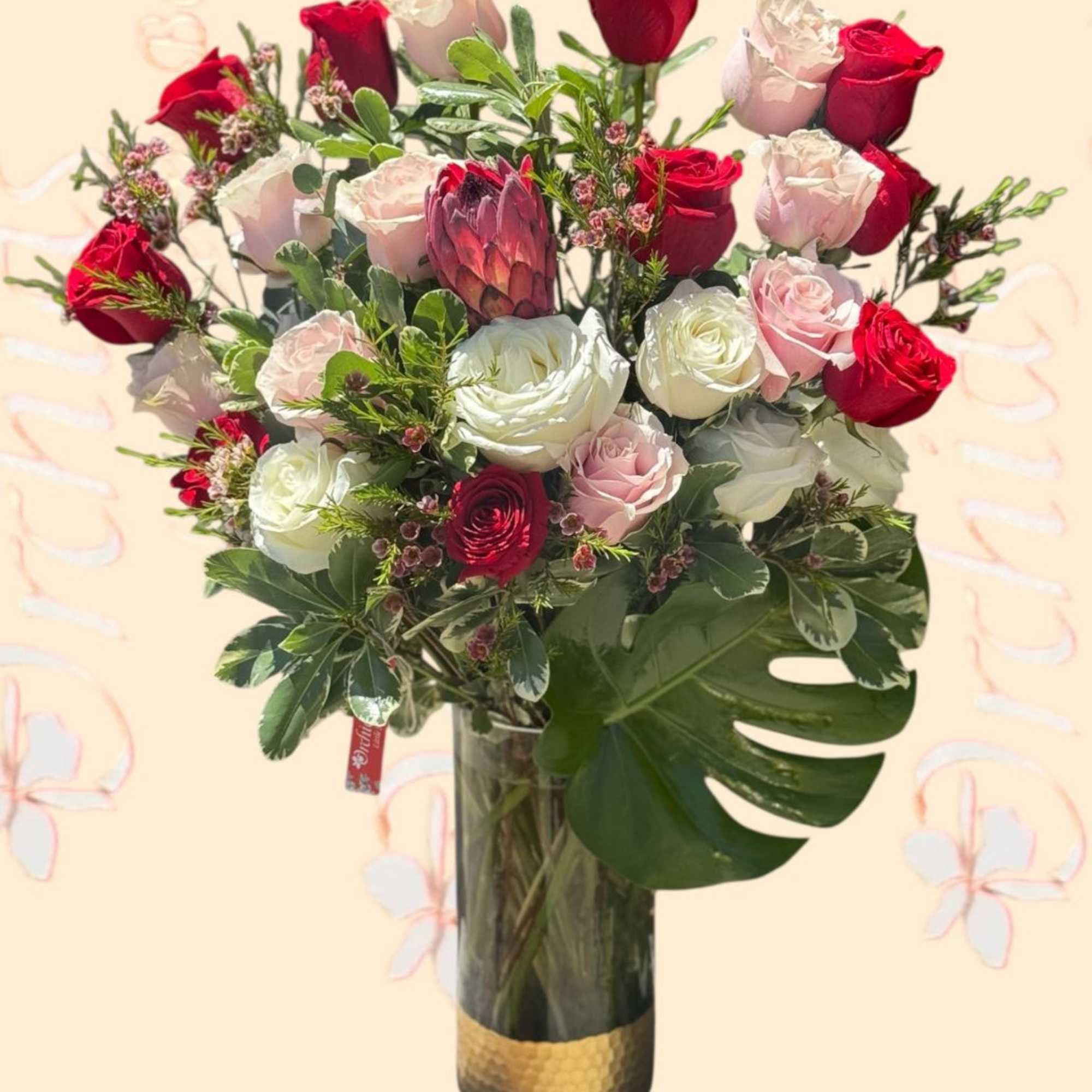 Bouquet of red, white, and pink roses in a tall glass vase