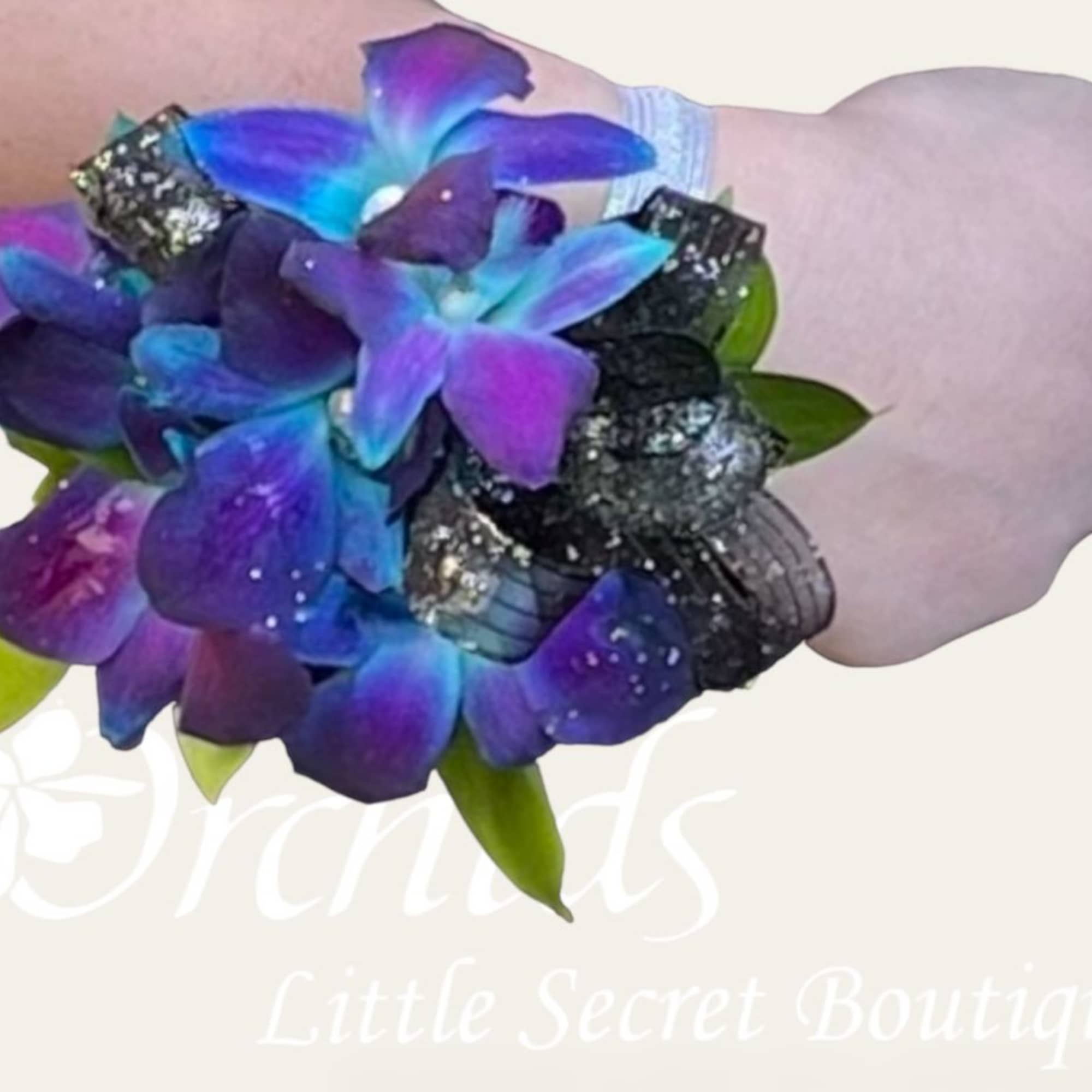 Purple and blue flower wrist corsage with black ribbon on a wrist
