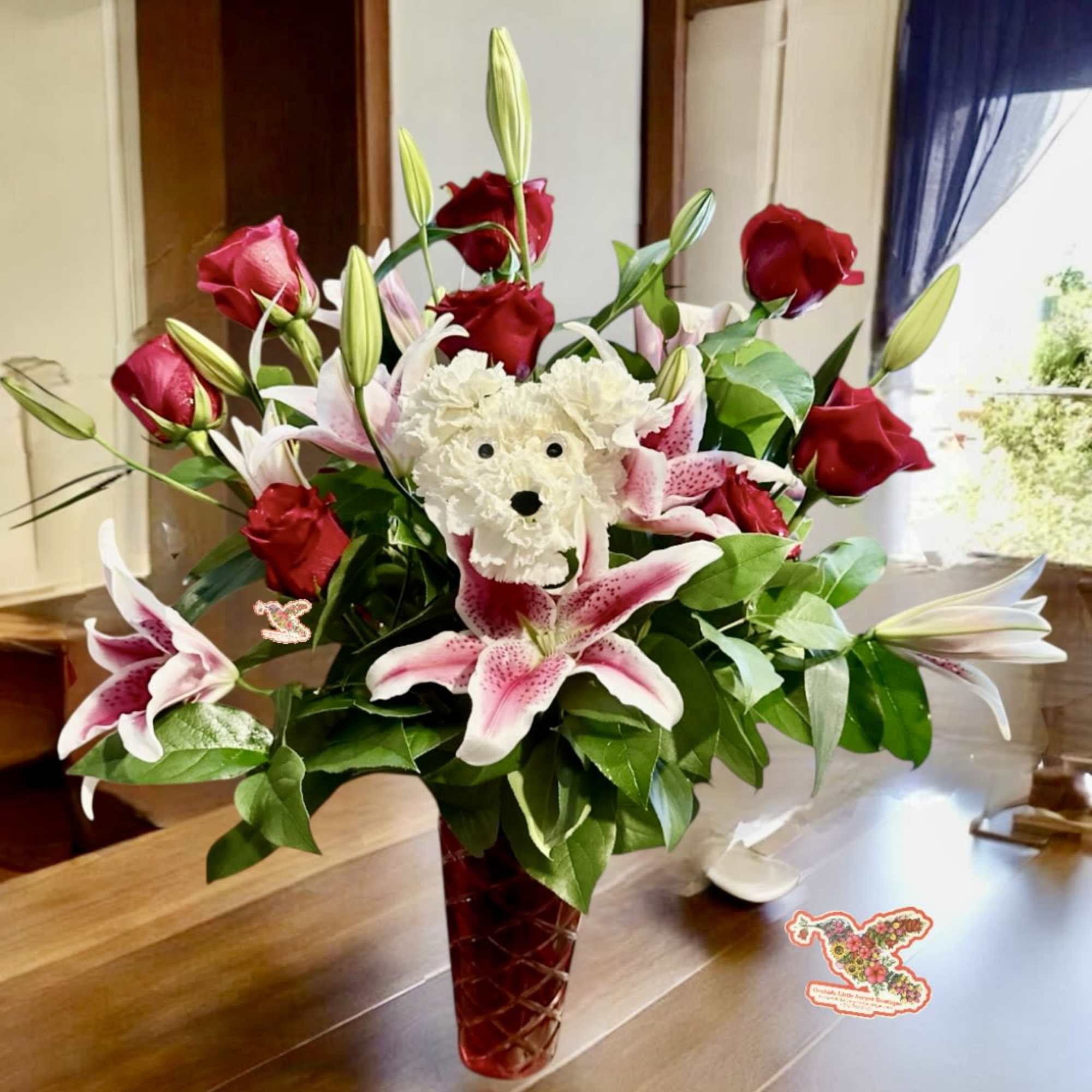 Bouquet of red roses and pink lilies with a white flower bear in a red vase