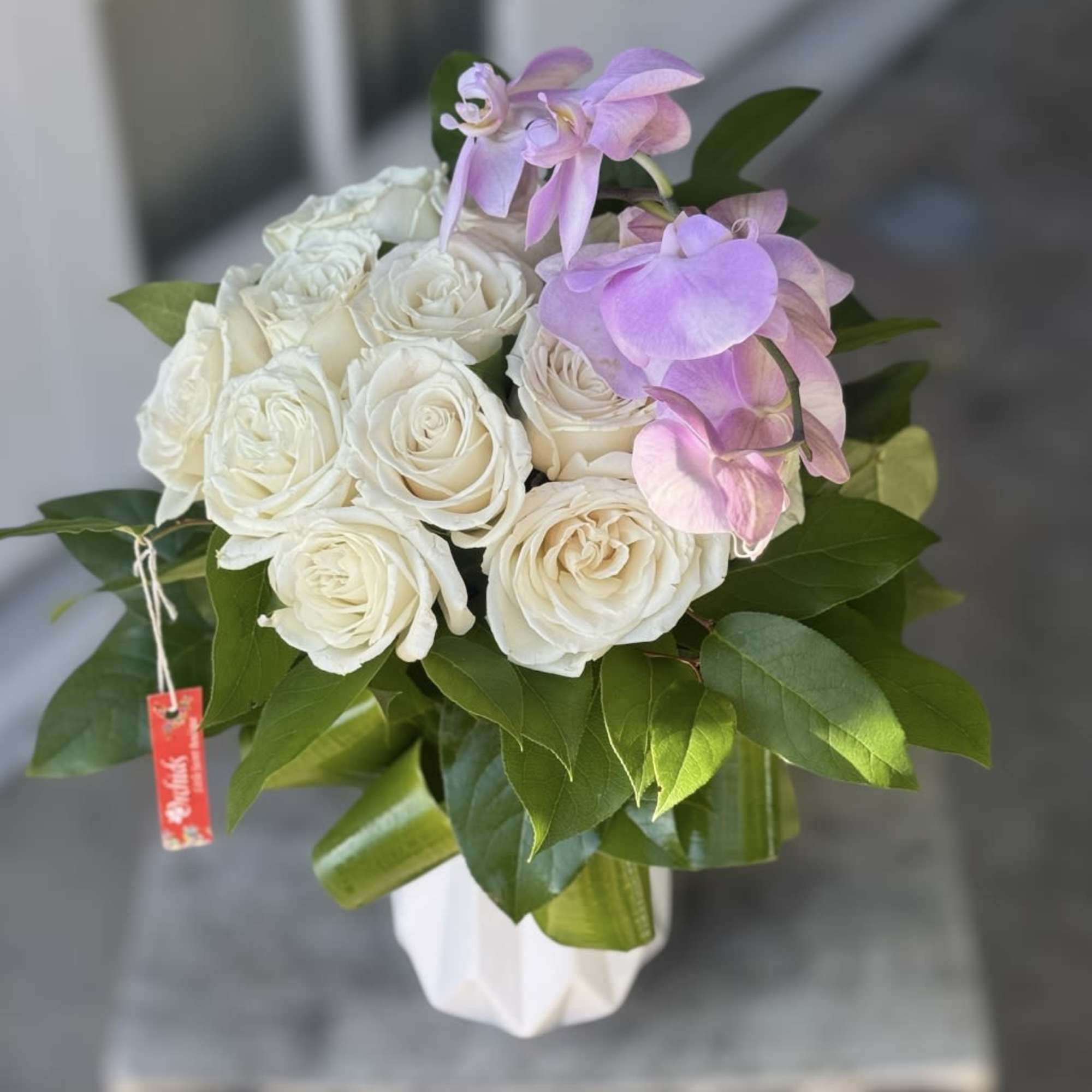 White roses and pink orchids in a white vase