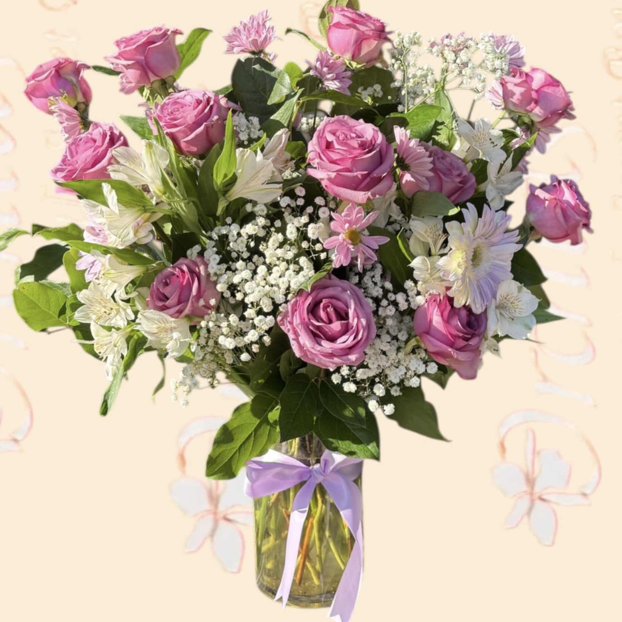 Pink roses and white flowers arranged in a glass vase with a lavender ribbon