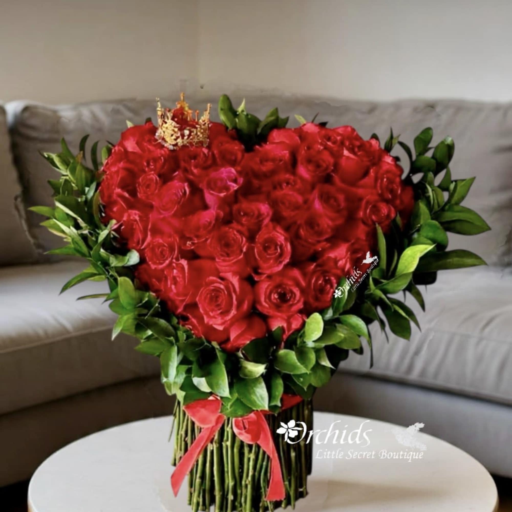 Heart-shaped bouquet of red roses with green foliage and a red ribbon, photo 2 of 2