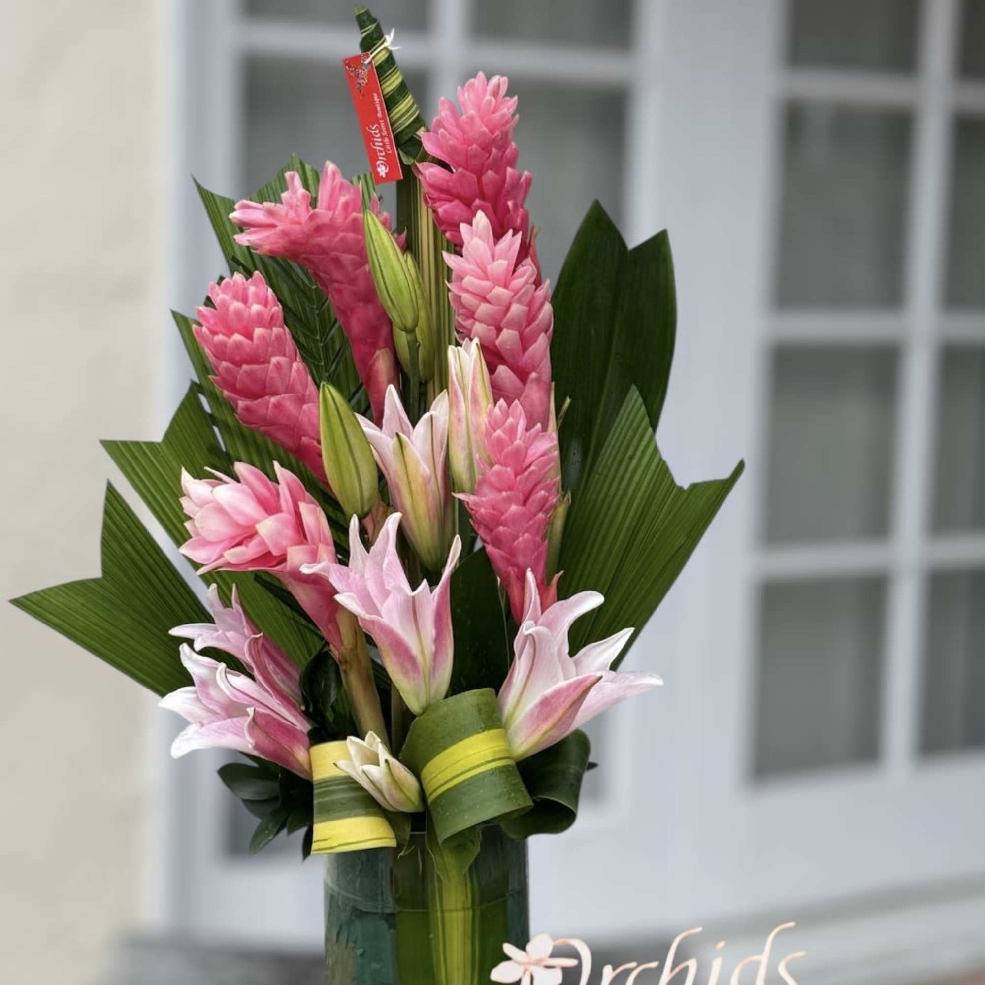 Pink ginger flowers and lilies arranged in a glass vase