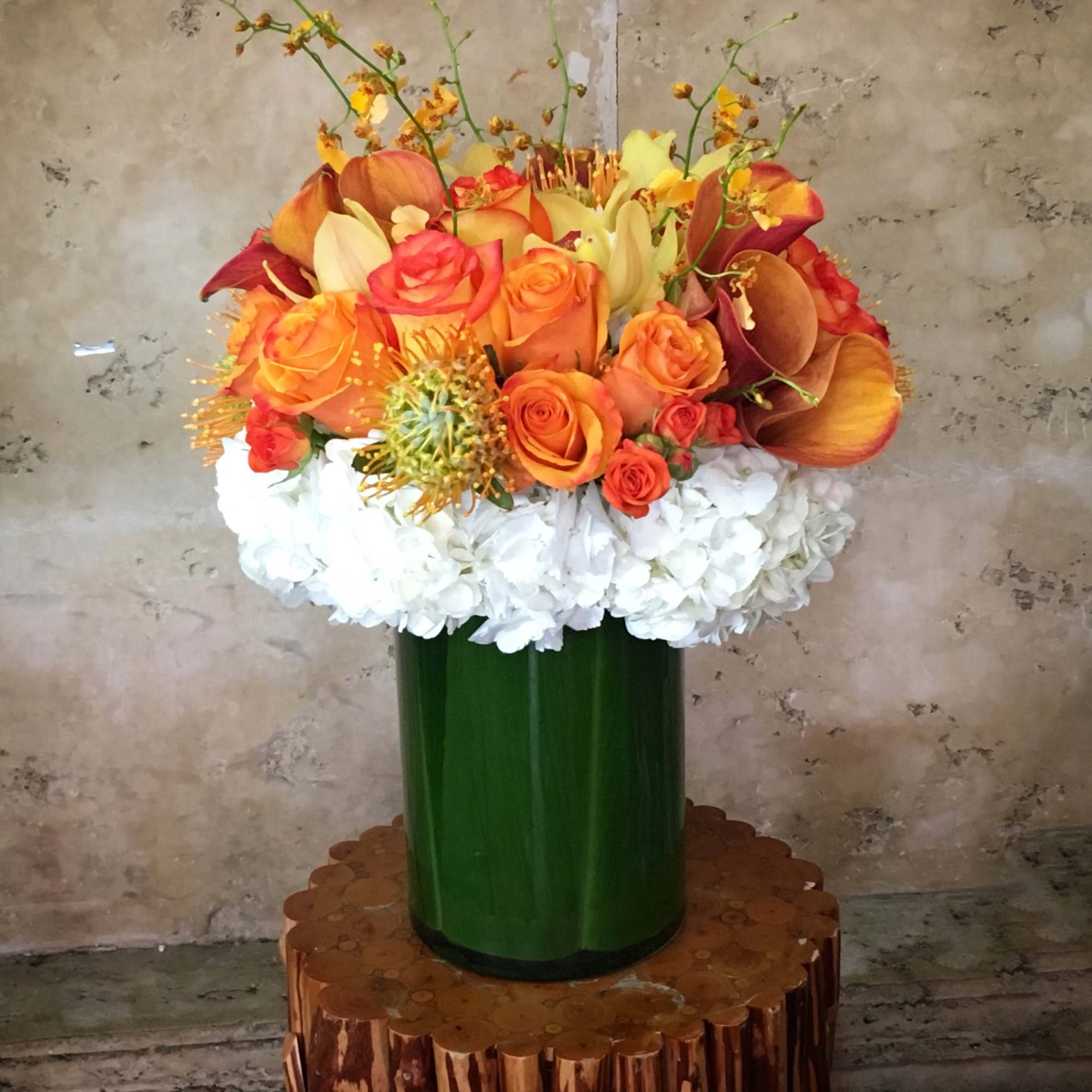 Orange and white floral arrangement in a green vase